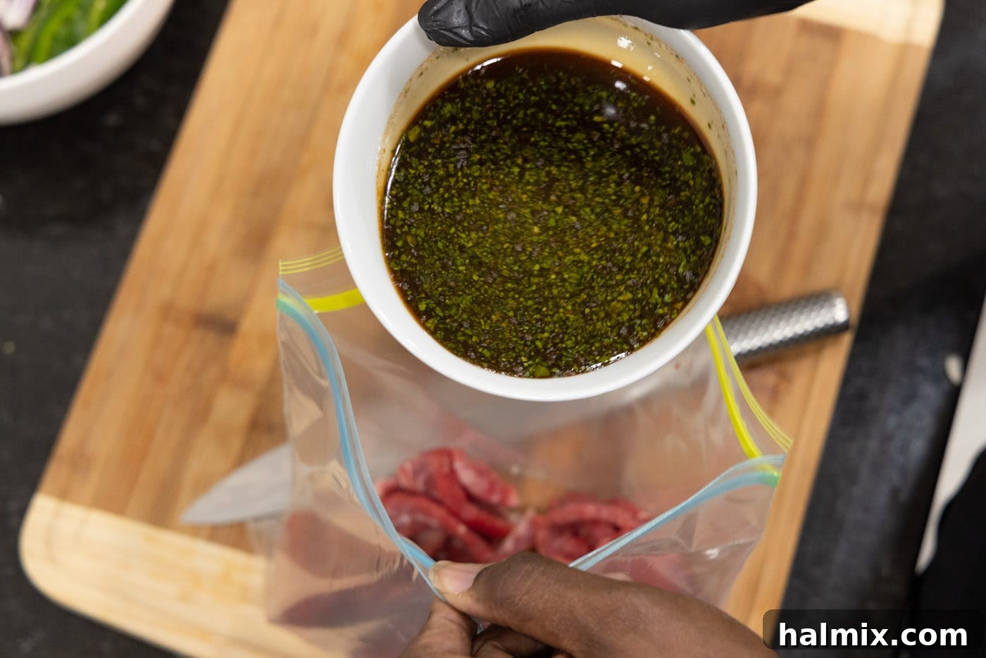 pouring steak marinade into bag with flank steak
