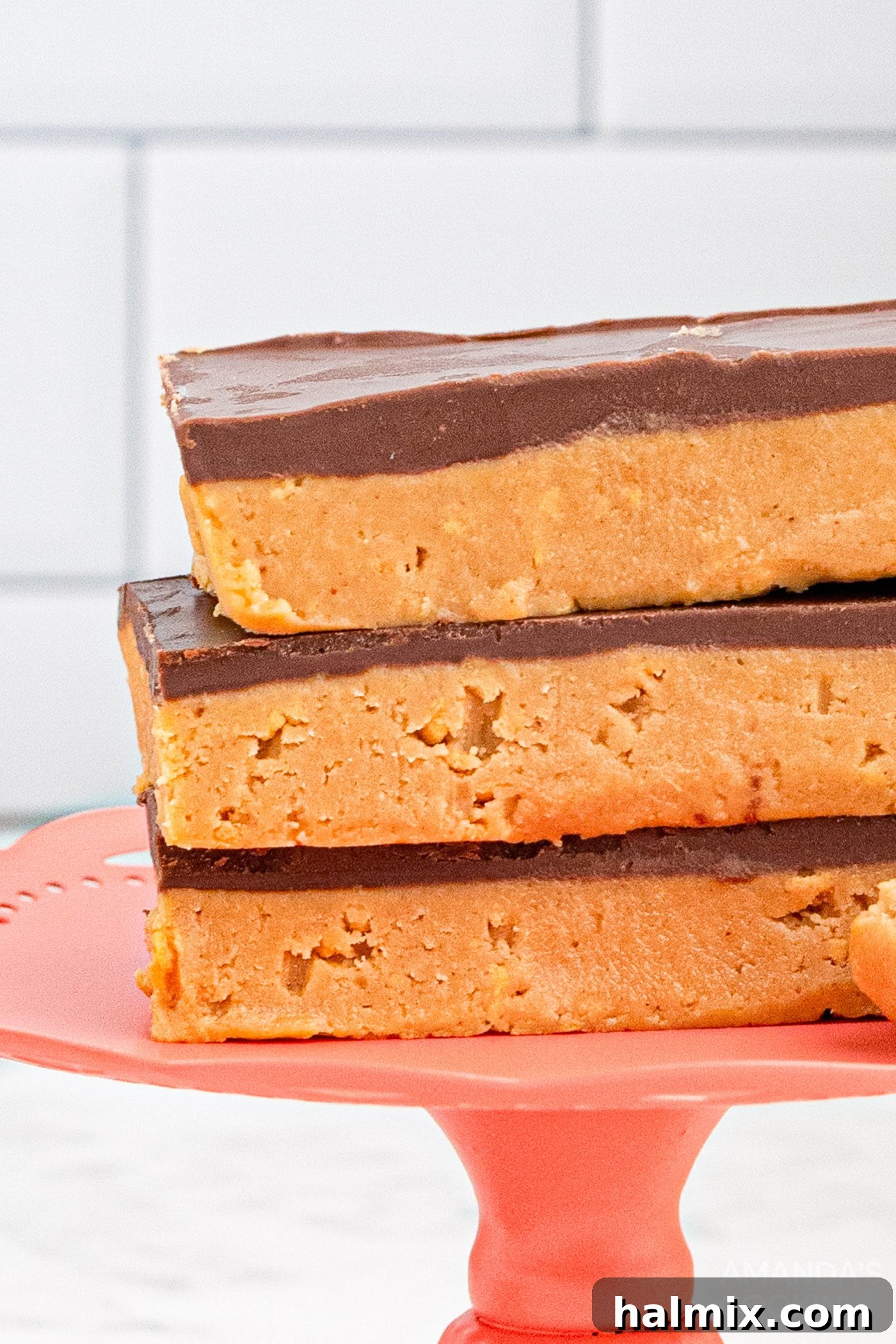 A close-up view of stacked no-bake peanut butter bars, highlighting the smooth chocolate ganache and crumbly peanut butter layer.