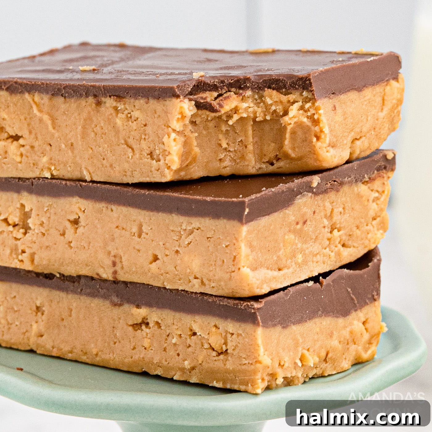 Three perfectly cut no-bake peanut butter bars, showing their distinct layers and tempting chocolate topping.