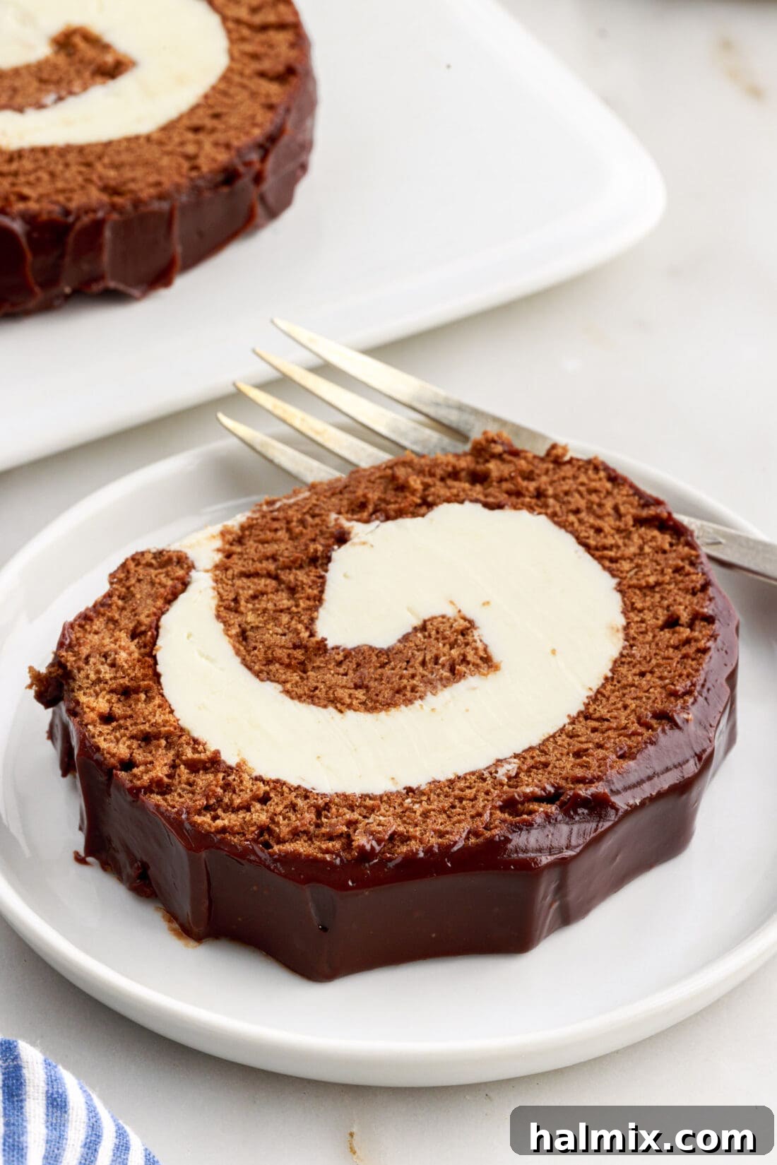 Decadent Chocolate Swirl Cake 3 A single slice of chocolate Swiss roll on a white plate, highlighting the detailed swirl