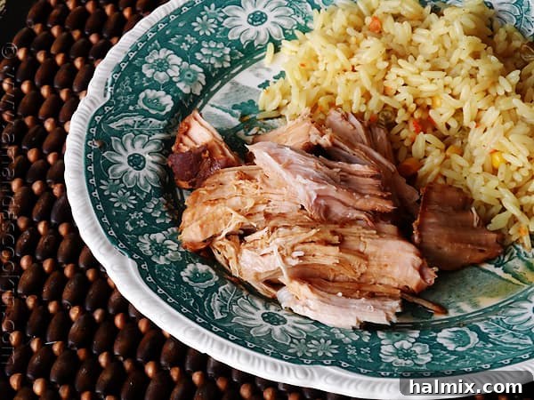 A close up photo of slow cooker oriental pork roast on a plate next to rice and steamed broccoli.