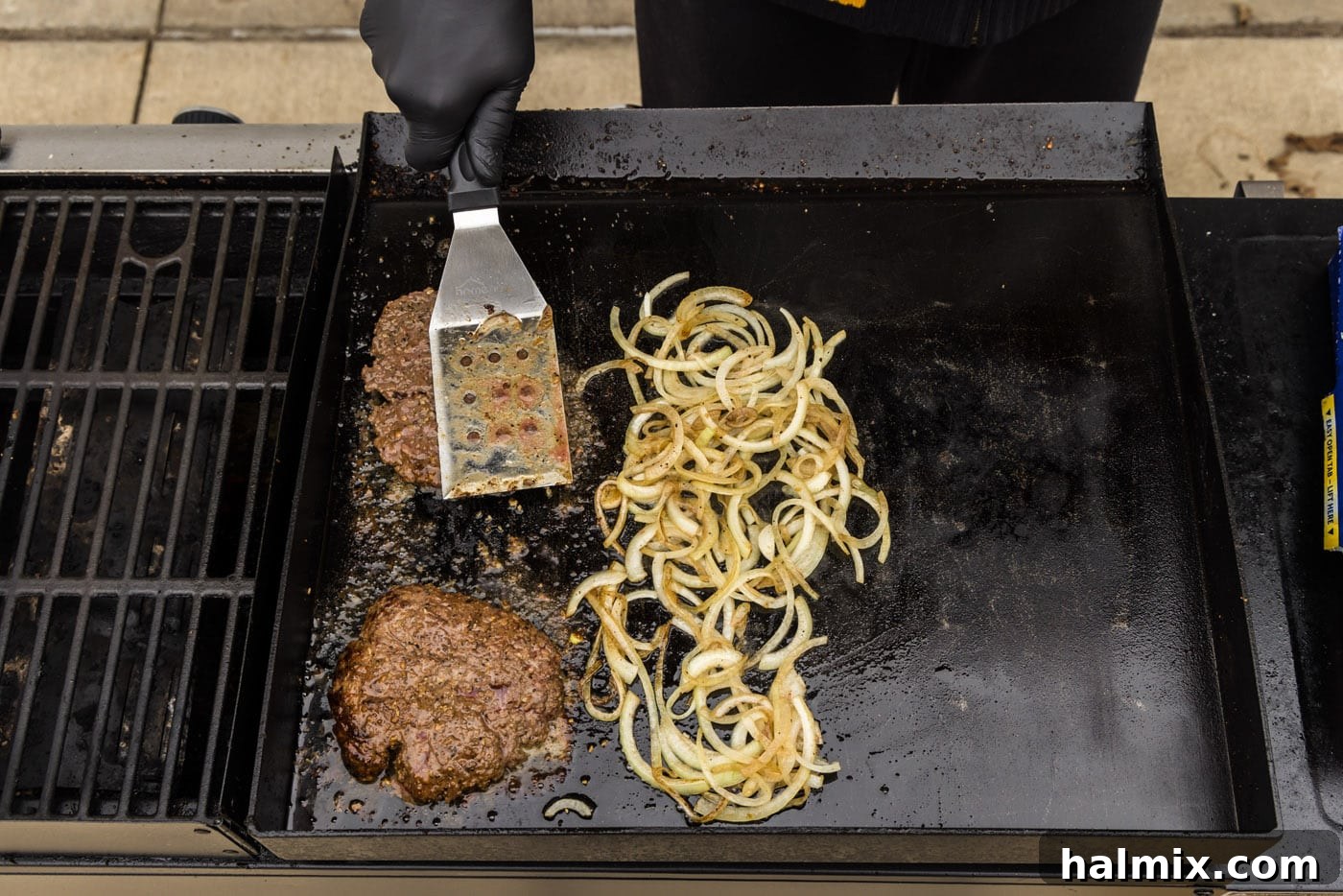 cooked burger patties with caramellized onions on a grill
