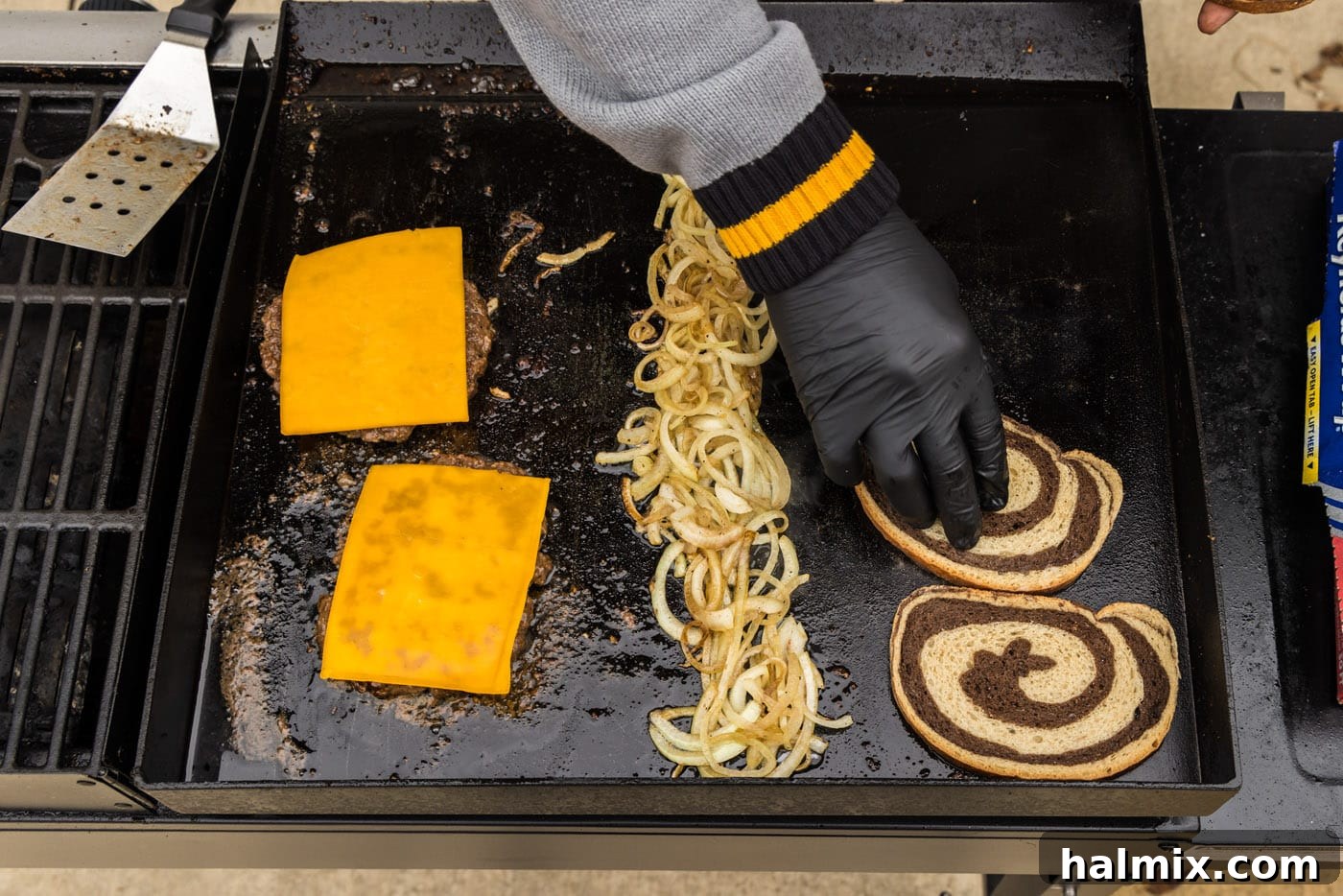 adding rye bread to grill with onions and burger patties