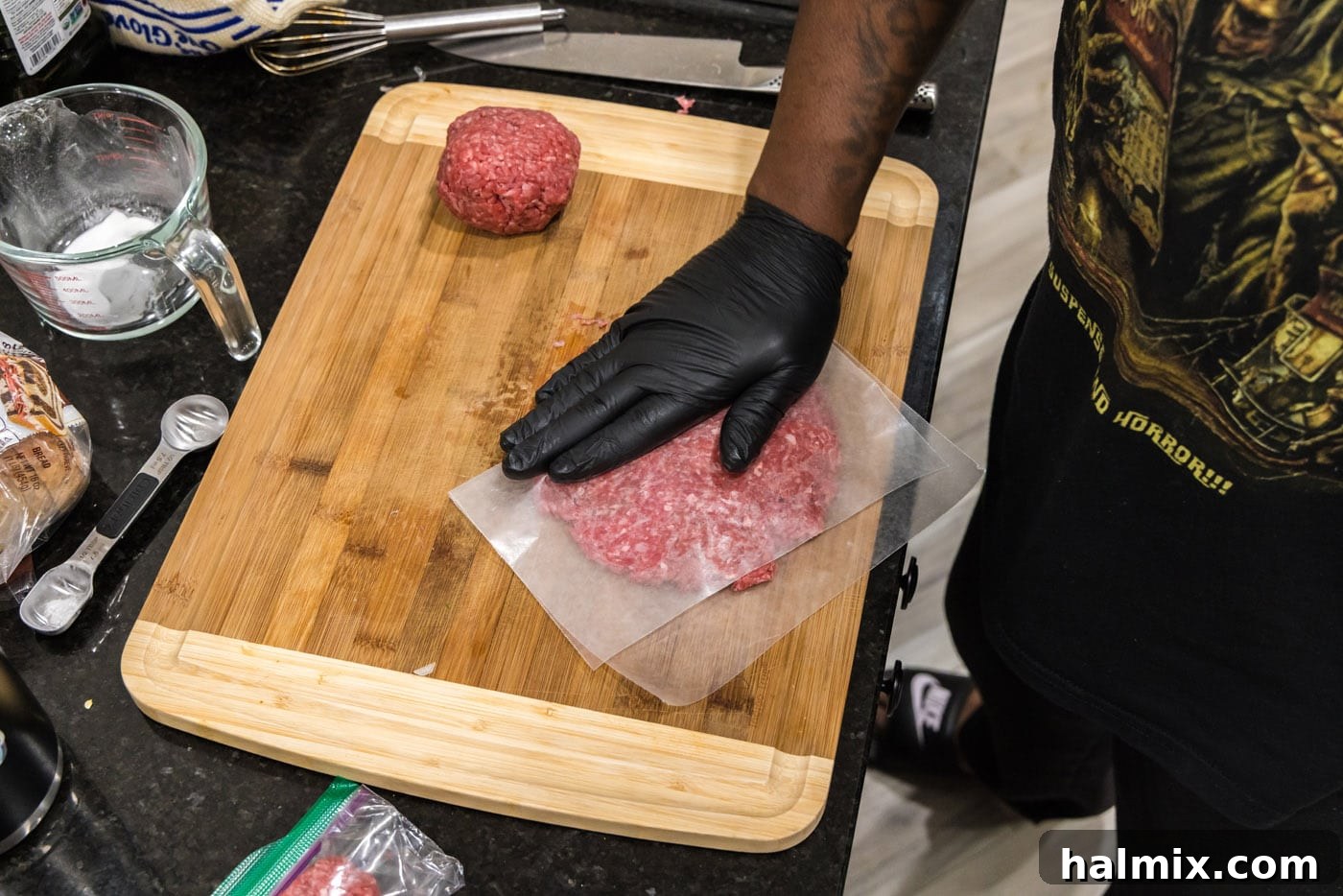 pressing down on parchment covered burger meat to flatten