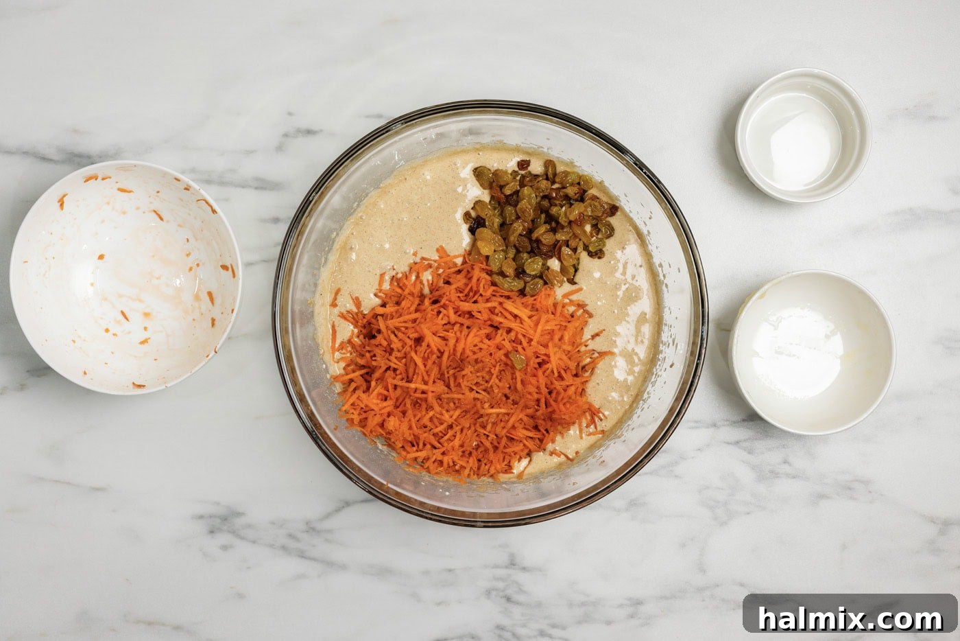 Decadent Carrot Cupcakes 6 shredded carrots and golden raisins added to spice cake batter in a bowl
