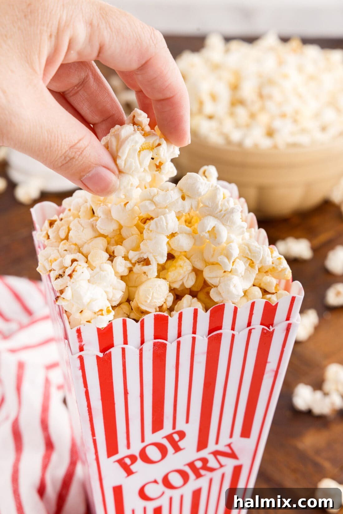 Hand grabbing Kettle Corn out of a fun popcorn bucket, ready to be enjoyed