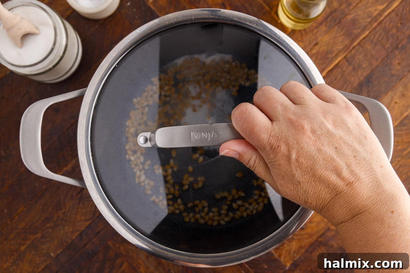 Placing the lid securely over the pot with popcorn kernels