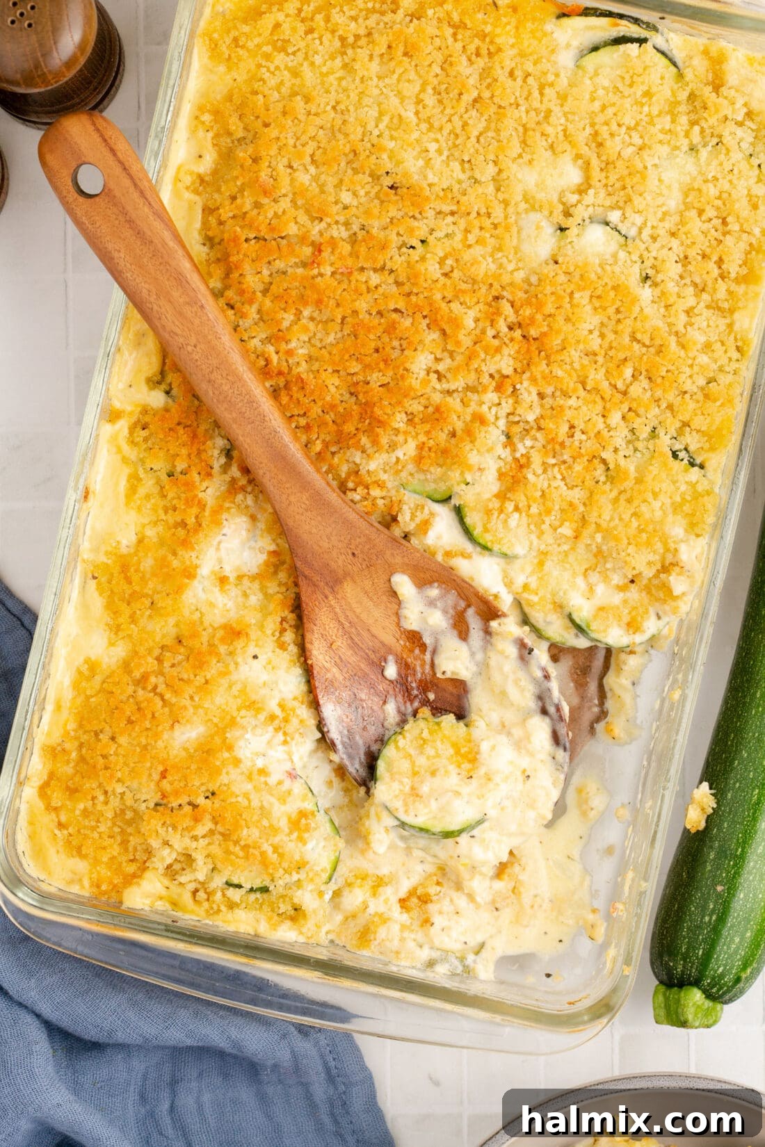 A spoon rests in a pan of creamy, cheesy Zucchini Casserole, showcasing its golden-brown topping and tender texture, inviting you to serve yourself.