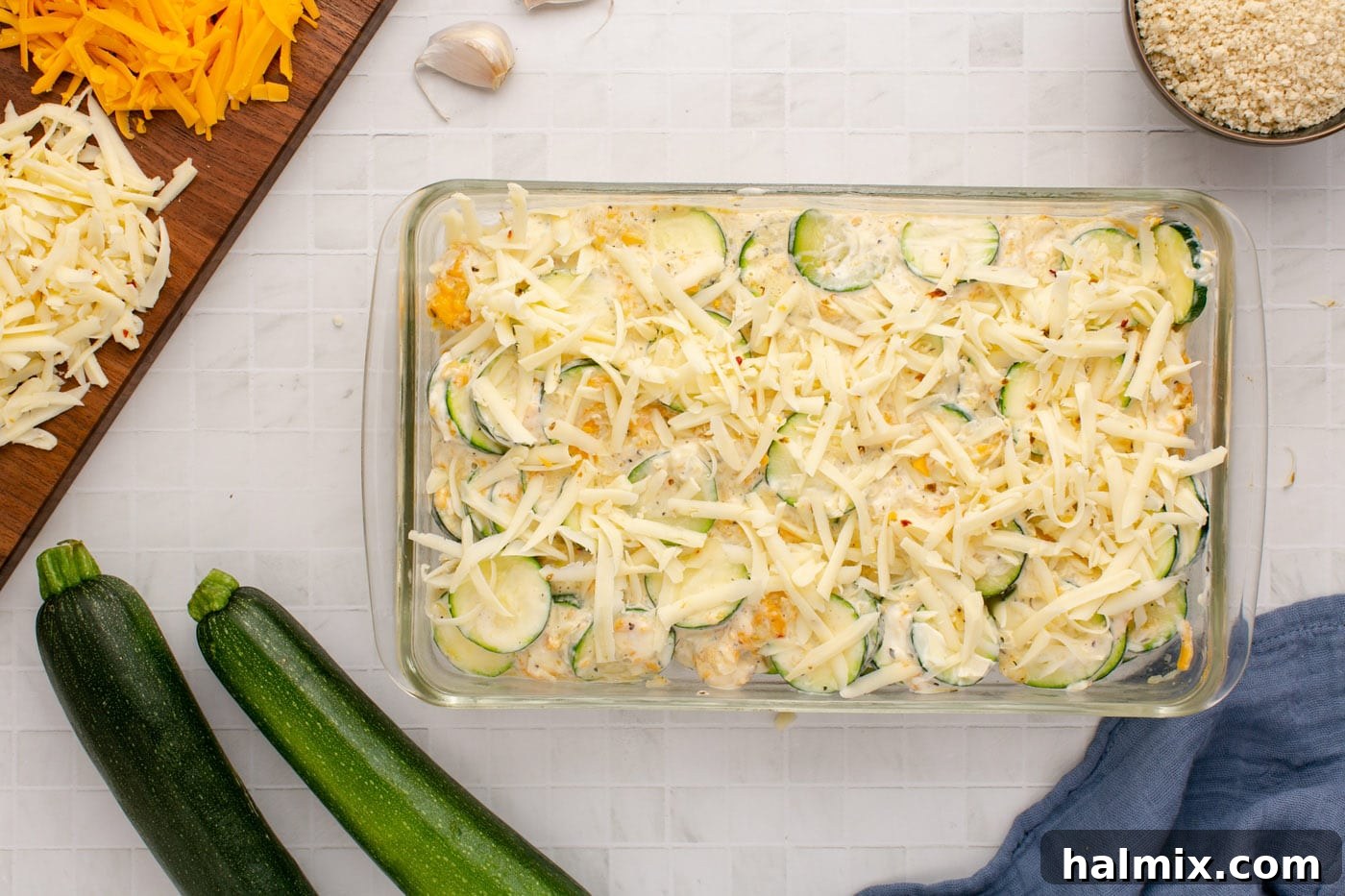 The zucchini casserole base now topped with an extra layer of Monterey Jack cheese, ready for baking.