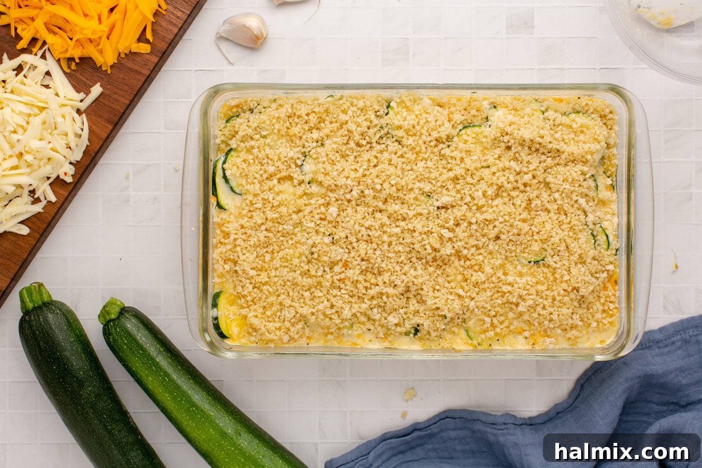The zucchini casserole, freshly baked and now topped with an even layer of buttered panko breadcrumbs, ready for broiling.