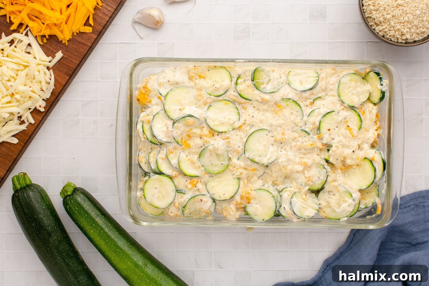 The creamy, cheesy zucchini mixture being spread evenly into the prepared baking dish, forming the base of the casserole.