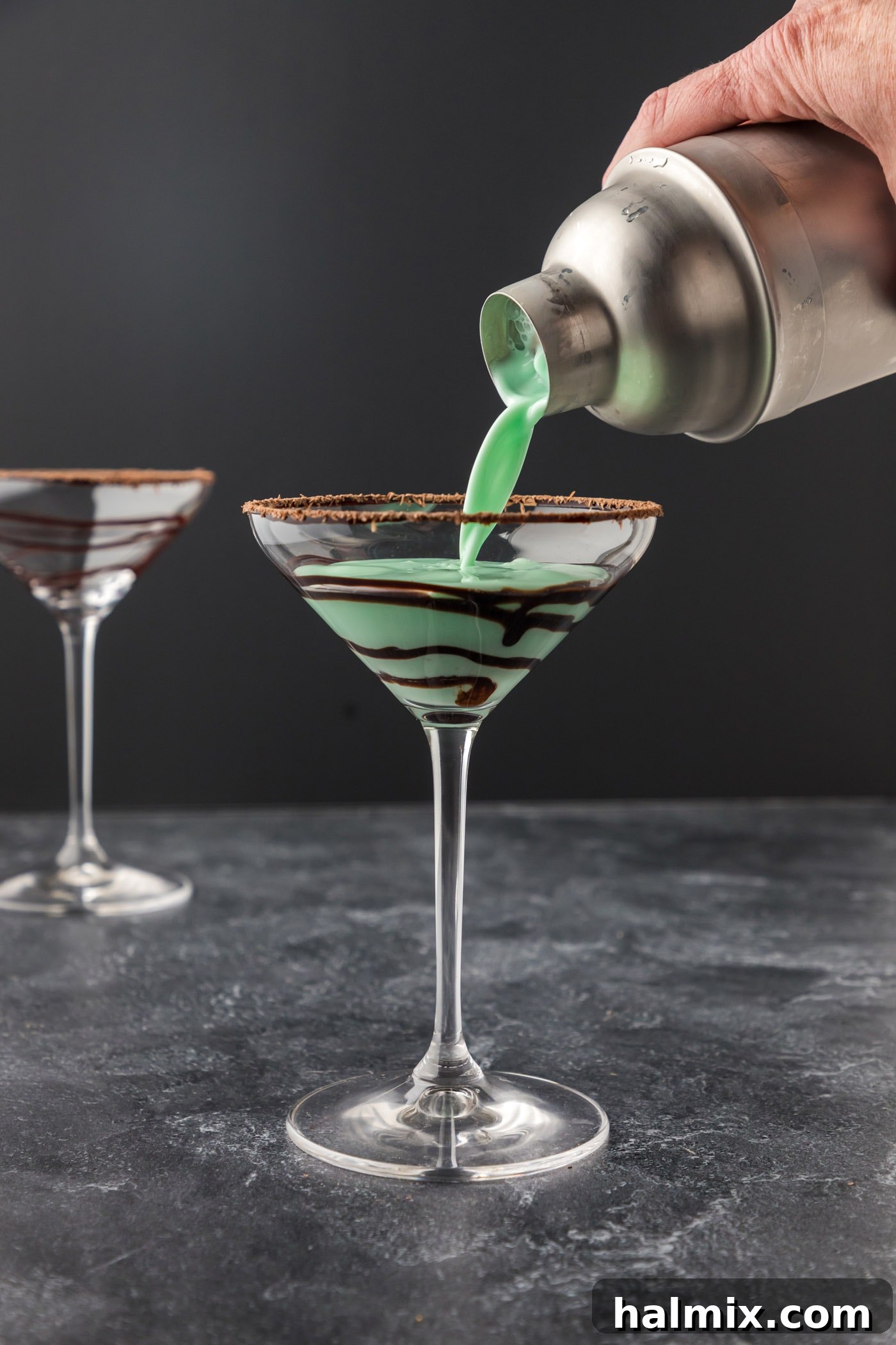 Straining the perfectly mixed Grasshopper cocktail from the shaker into a decorated martini glass.