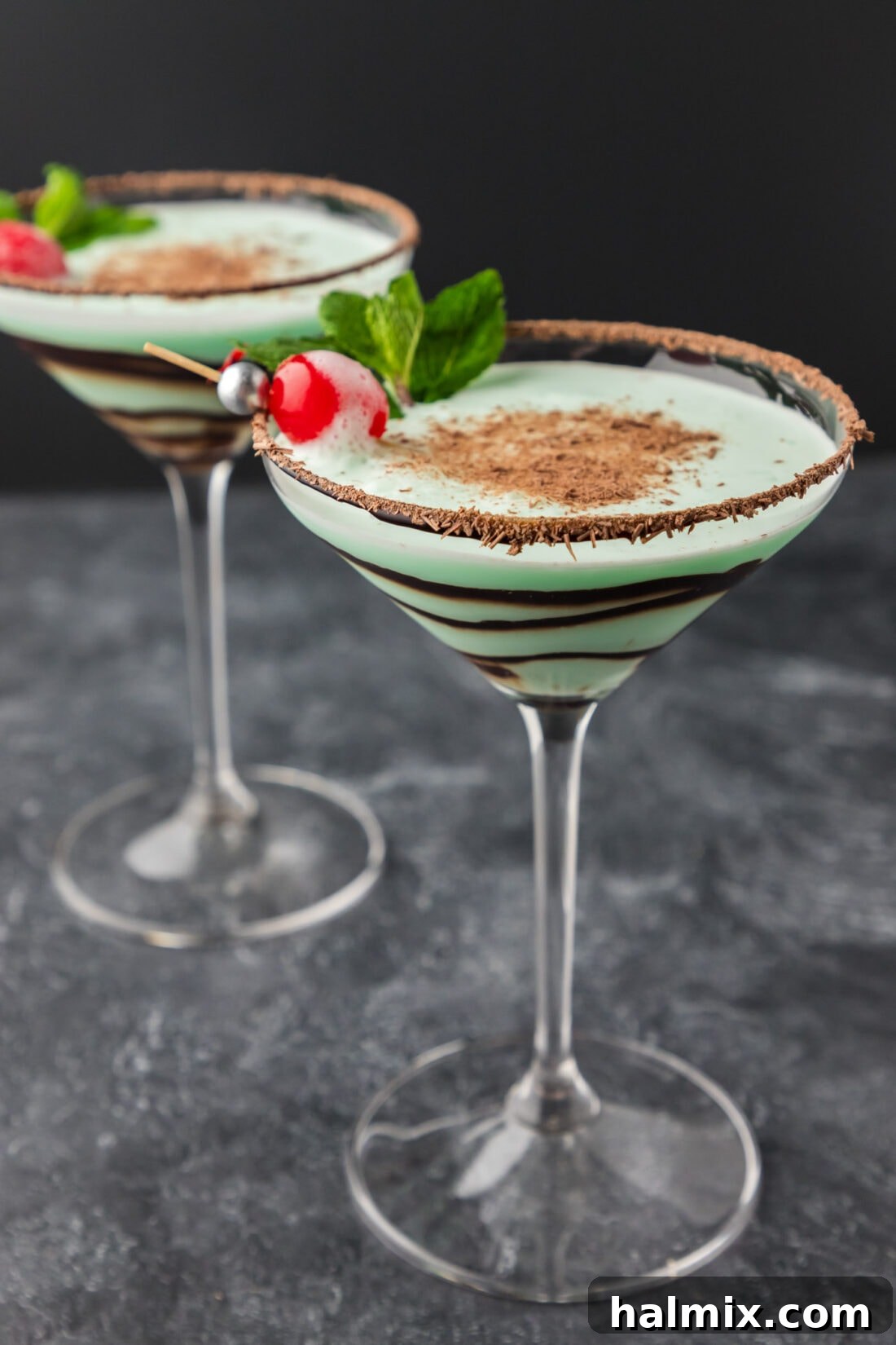 A close-up of two elegantly garnished Grasshopper drinks, highlighting their creamy texture and vibrant green color.