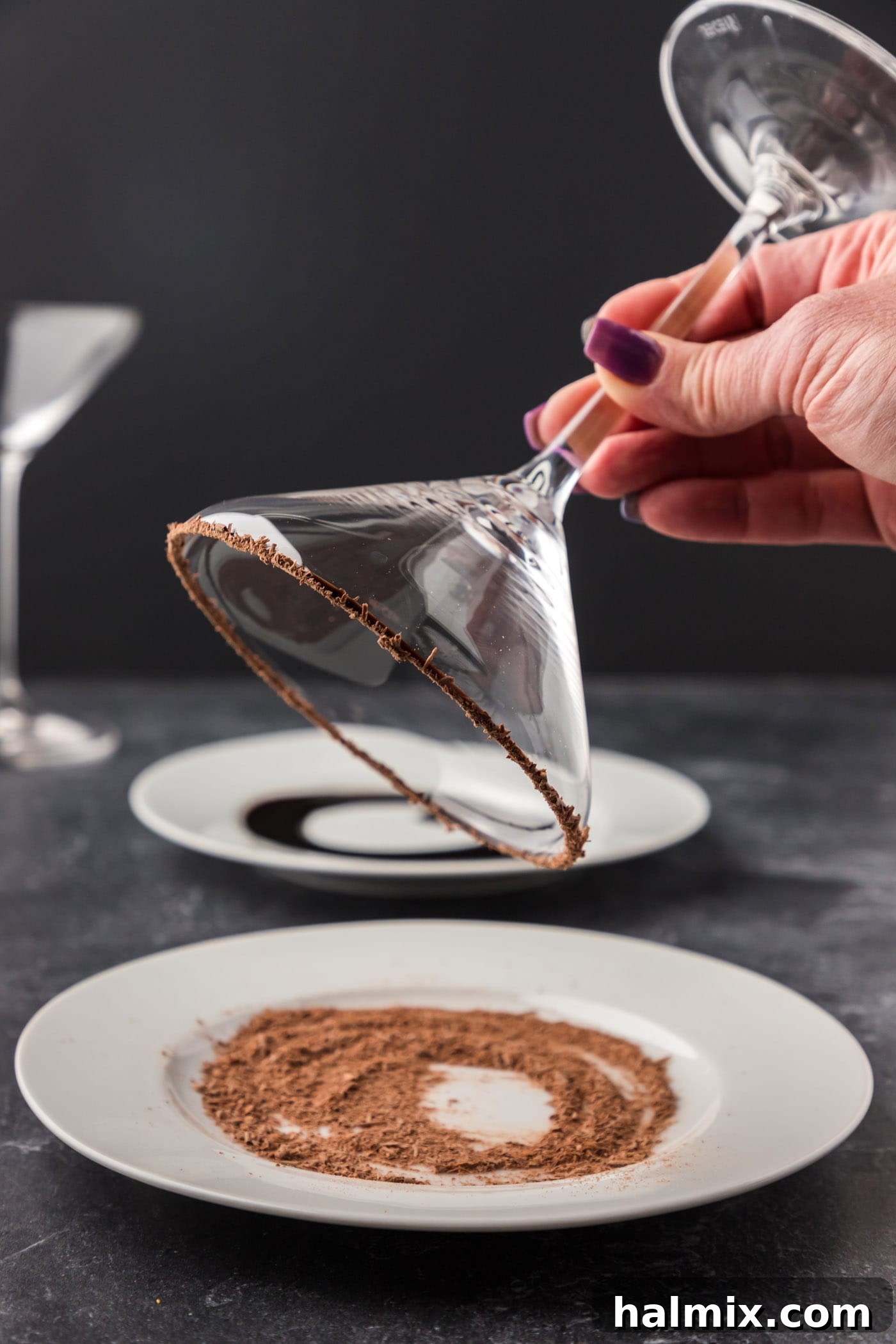 Rolling the chocolate-syrup-dipped rim of a cocktail glass in shaved chocolate for an elegant garnish.