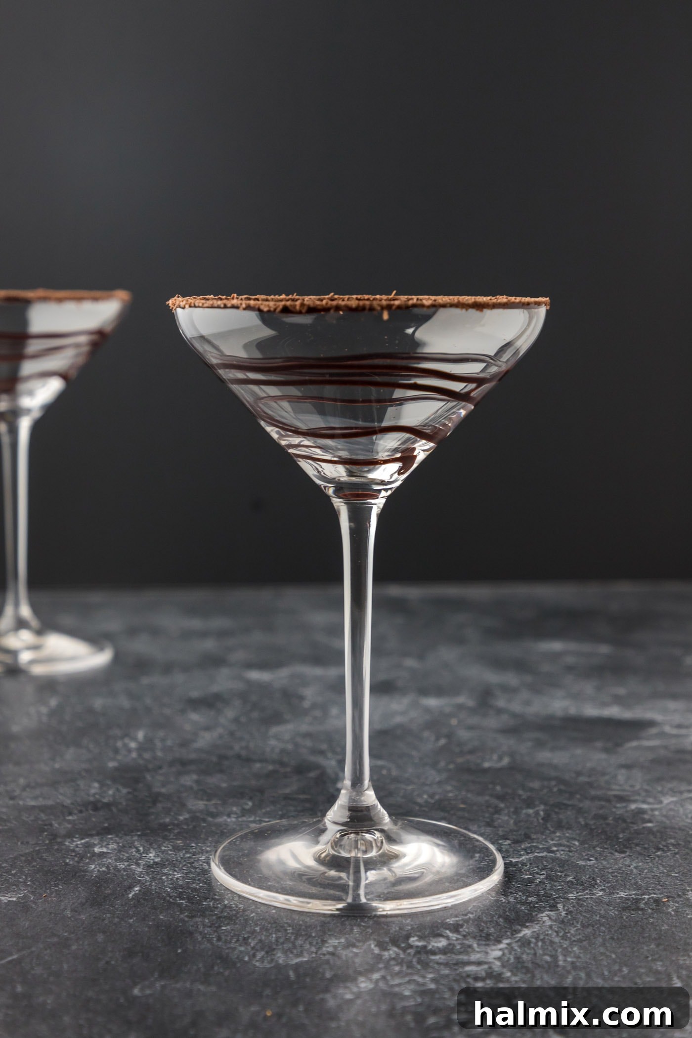 A martini glass elegantly drizzled with chocolate syrup on the inside, ready for a Grasshopper cocktail.