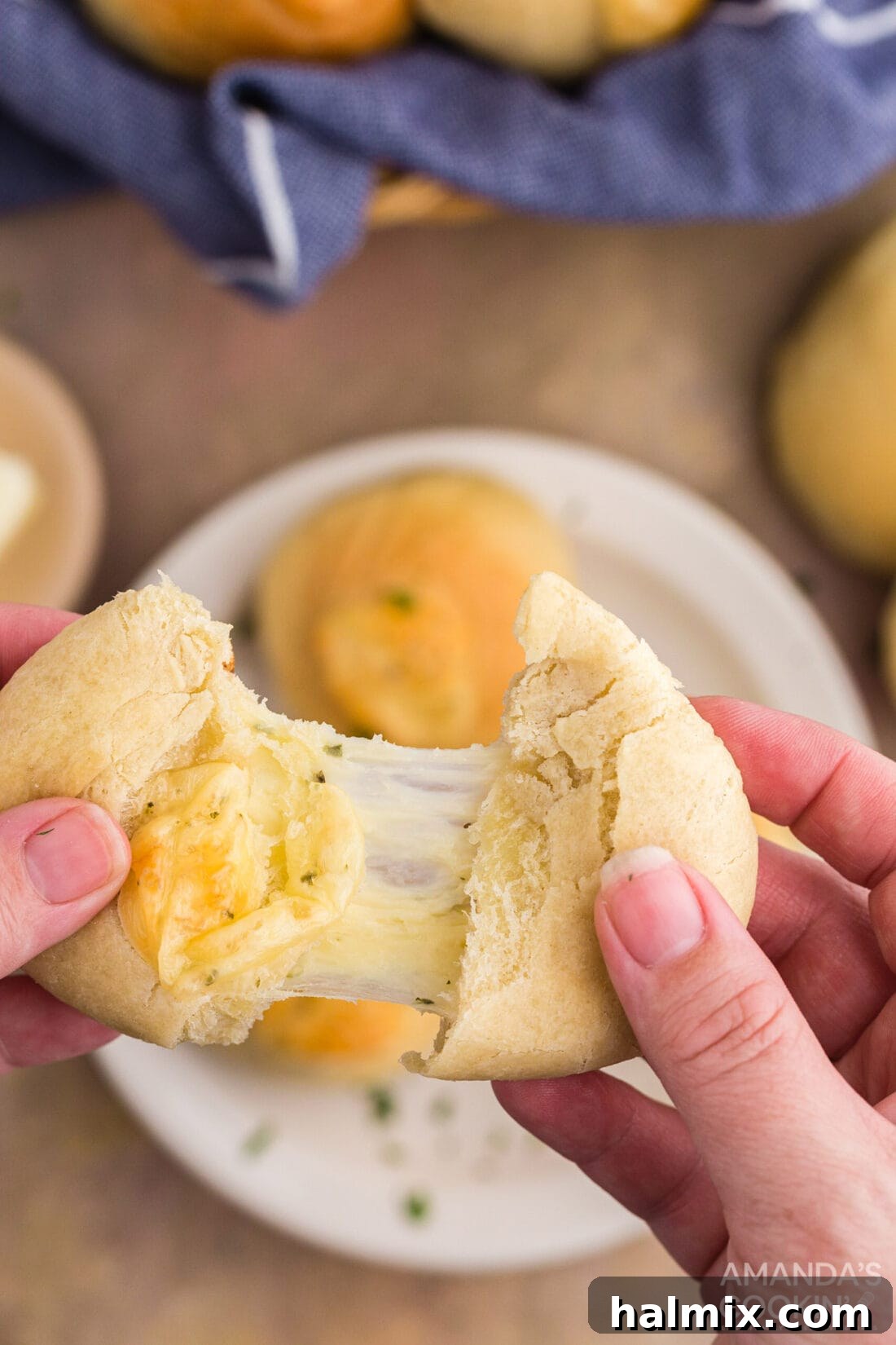A hand pulling apart a warm garlic cheese roll, revealing the gooey, melted cheese inside.