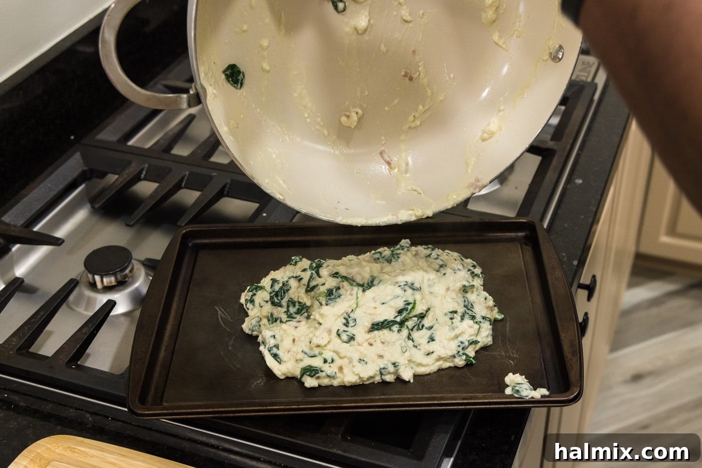 Pouring the prepared salmon stuffing onto a baking sheet to cool down before handling and stuffing the salmon fillets.