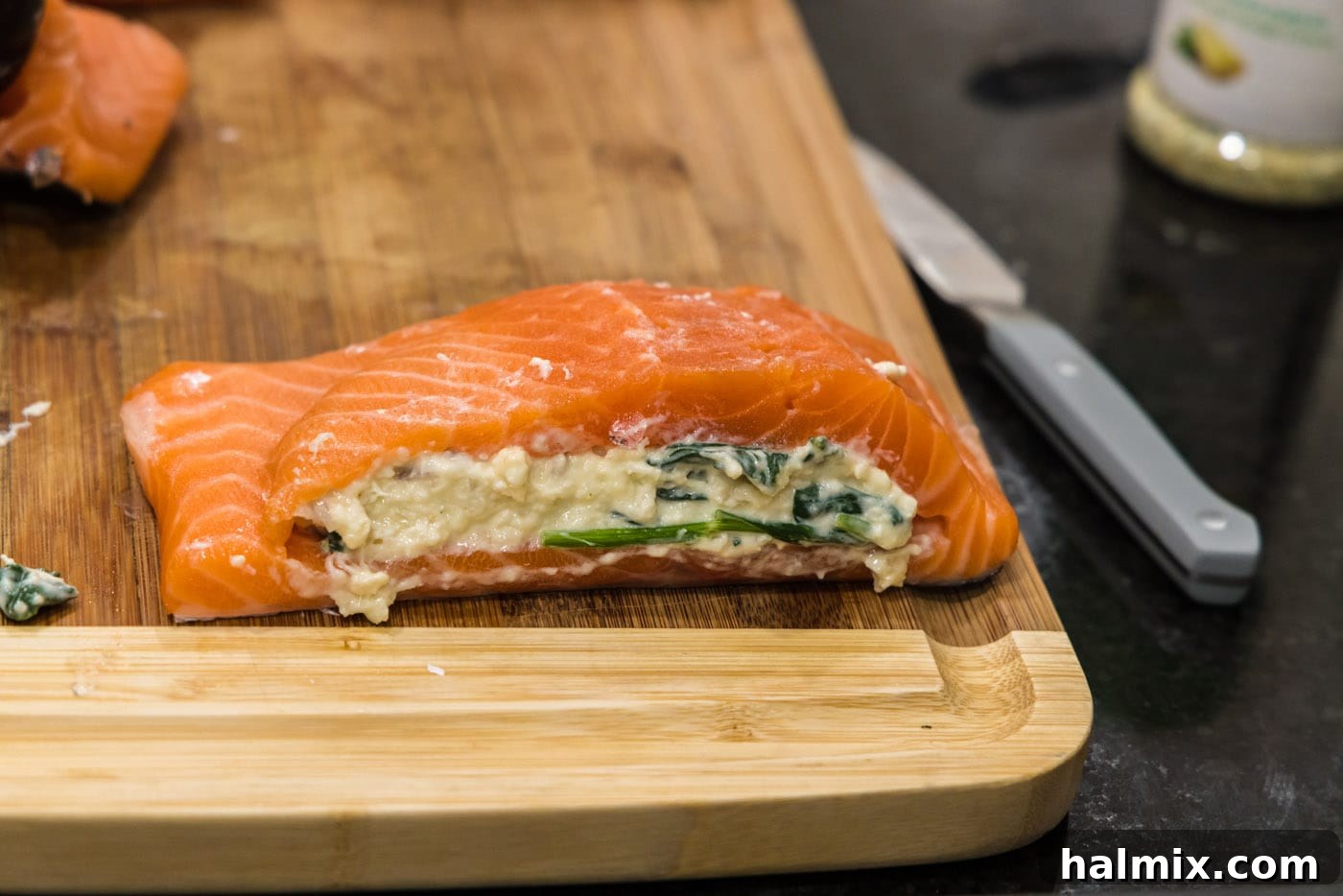 A salmon fillet beautifully stuffed with the savory filling, ready for seasoning and searing.