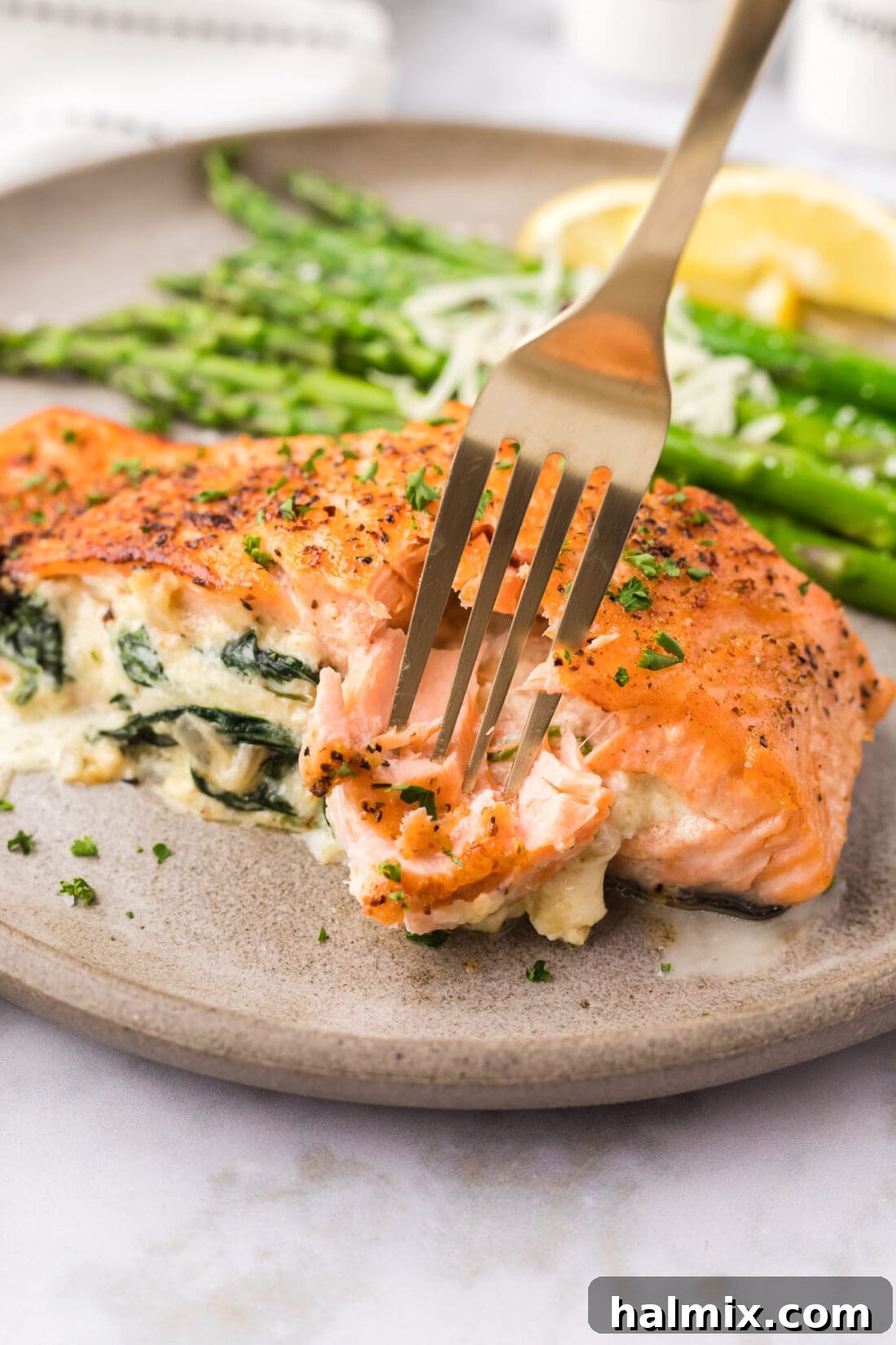 A fork gently breaking off a piece of flaky stuffed salmon, revealing the rich, creamy filling within, illustrating its perfect doneness.