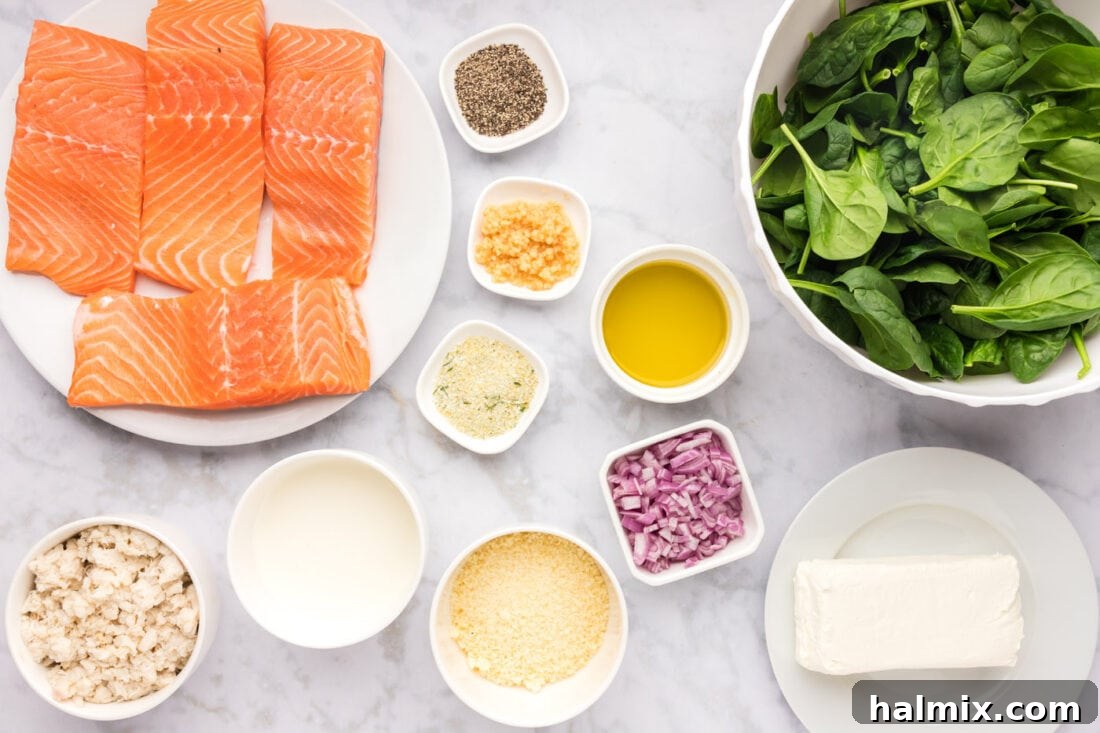 A collection of fresh ingredients laid out on a kitchen counter, including salmon fillets, spinach, cream cheese, crab meat, garlic, shallots, and heavy cream, ready for preparing stuffed salmon.