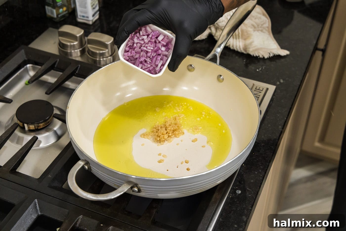Adding shallots to a hot pan with olive oil and minced garlic, beginning the savory stuffing base.