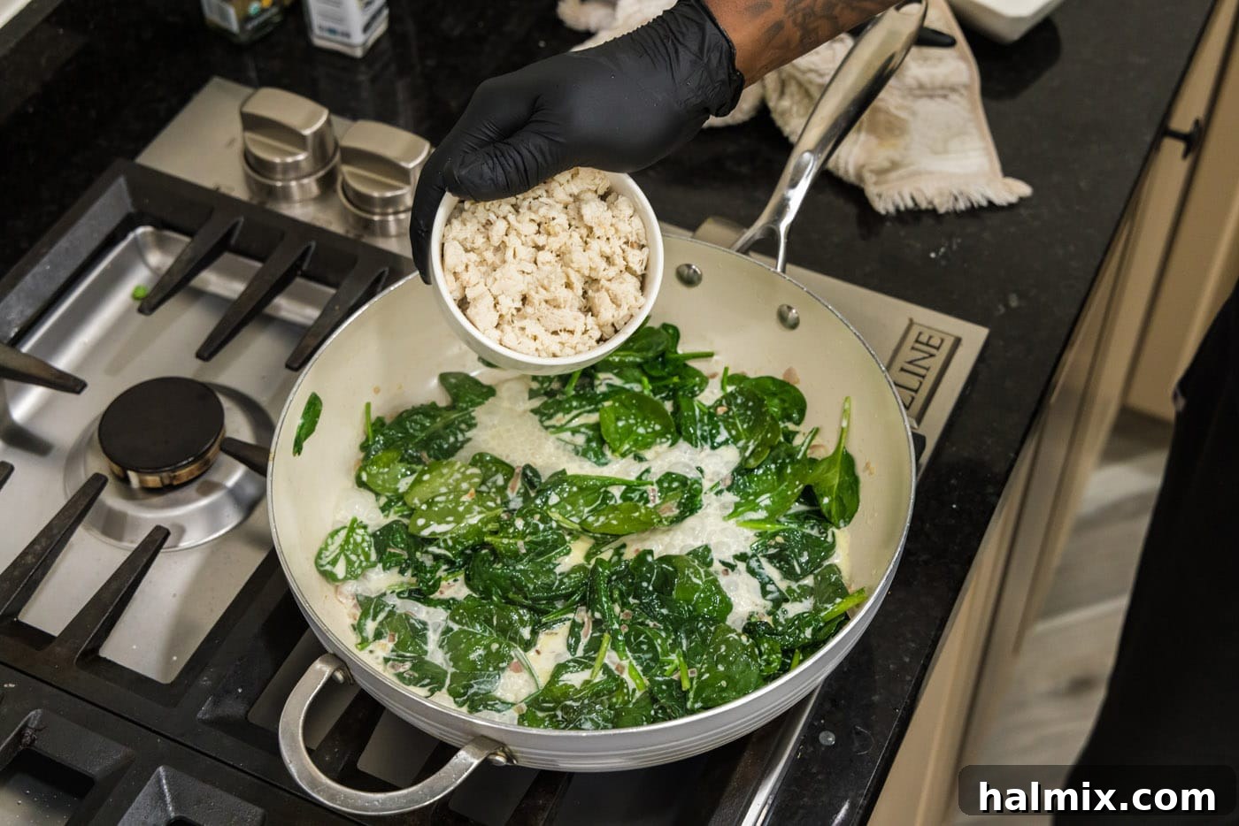 Adding cooked crab meat to the spinach and cream mixture in the skillet, enriching the seafood stuffing.