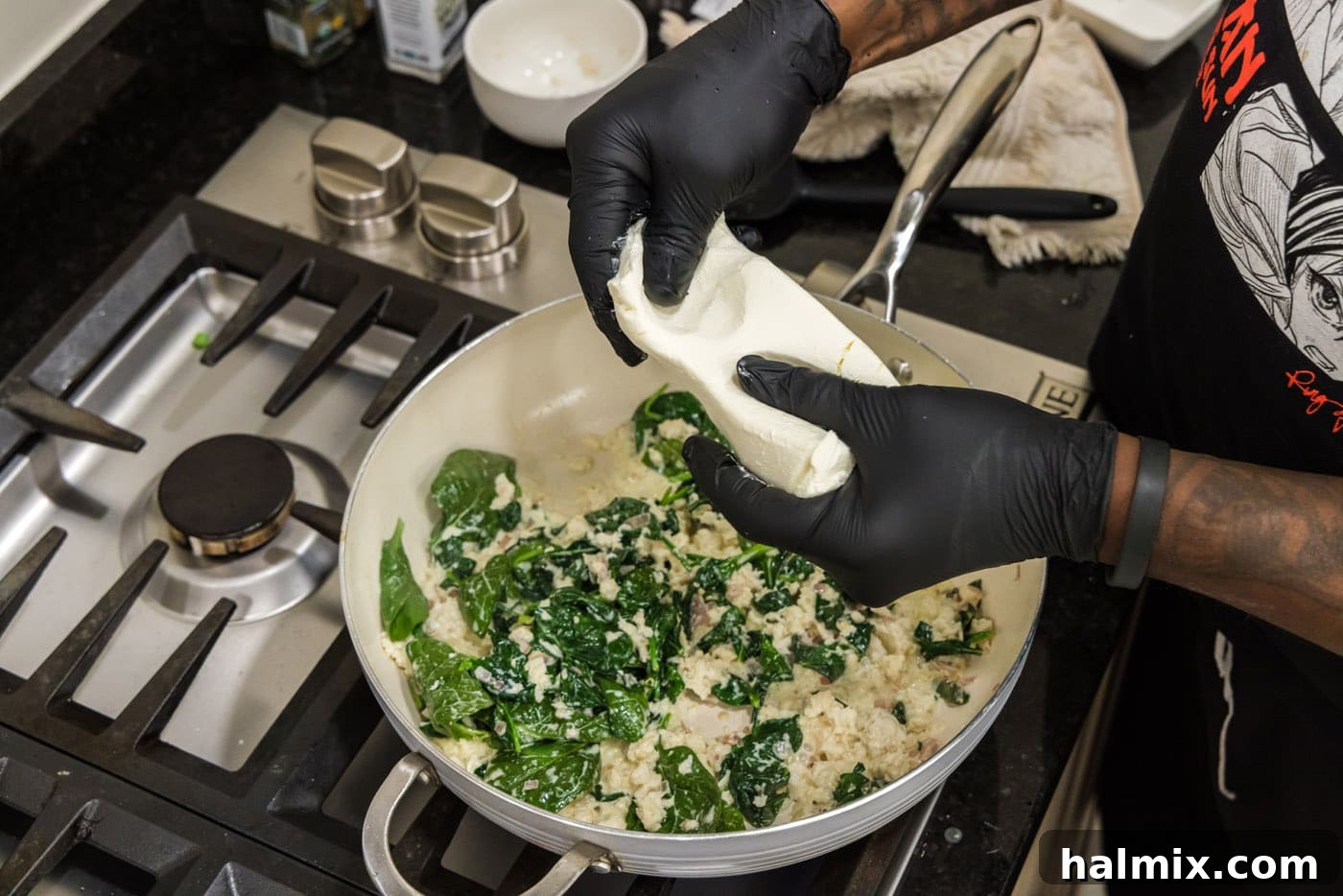 Hands gently squeezing softened cream cheese, preparing it to be added to the skillet for the stuffing mixture.