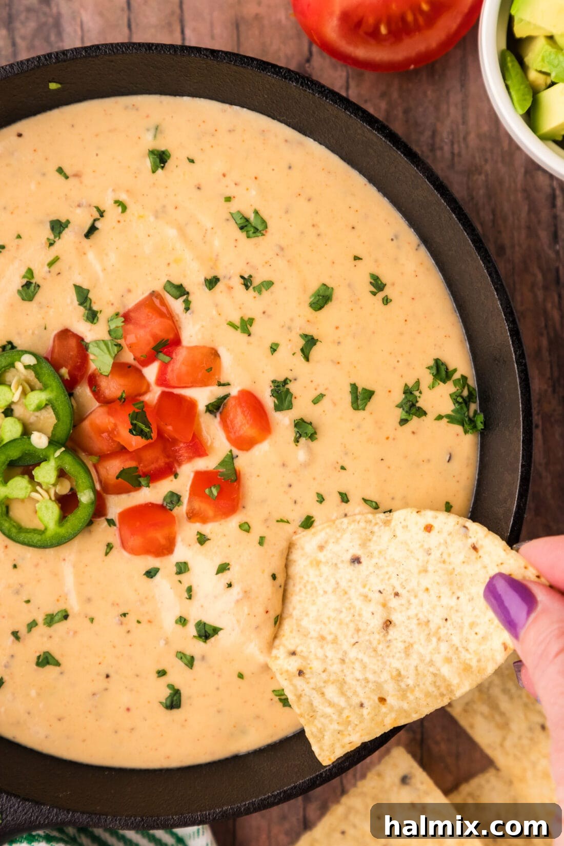 Tortilla chip being dipped into a skillet of Queso Dip