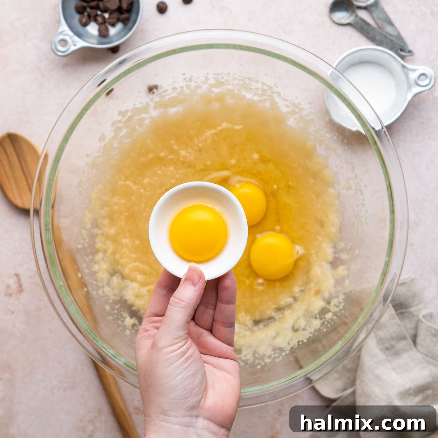 adding egg yolk to brownie batter in a bowl