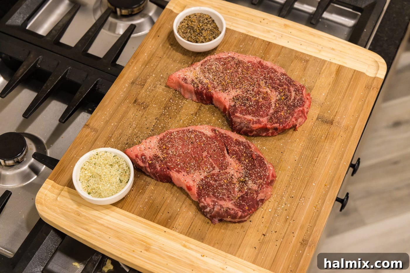 ribeye steaks on cutting board seasoned with garlic salt and steak seasoning