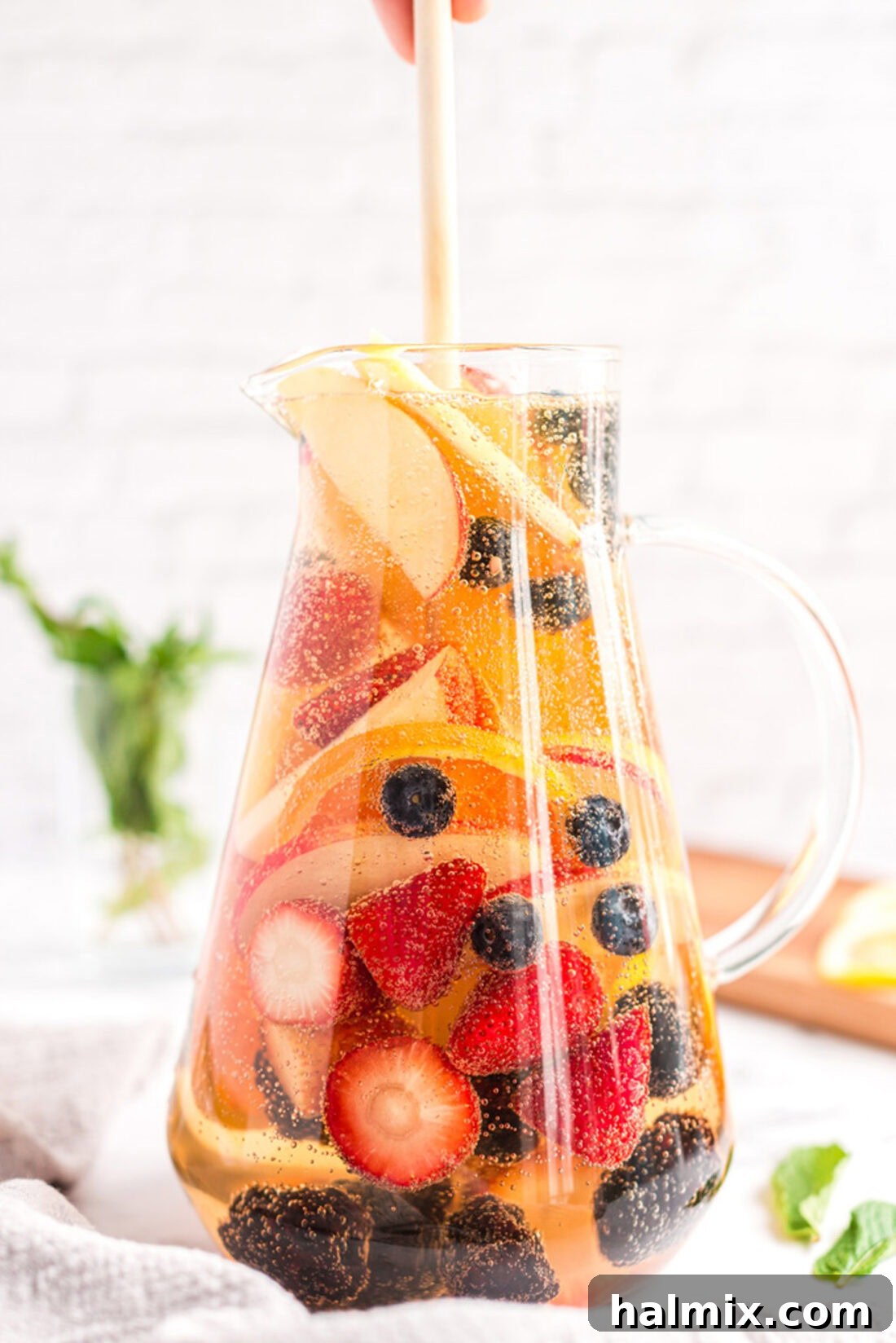 Sun-Kissed Sangria 3 A large pitcher of homemade white sangria, filled with sliced fruit like oranges, lemons, and berries.