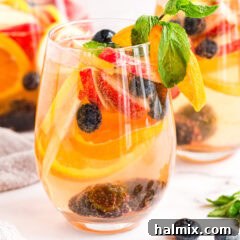 glass of white moscato sangria, garnished with fresh fruit and mint.