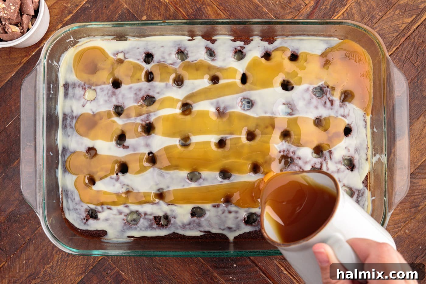 Thick caramel sauce being drizzled over the top of the cake, already soaked with condensed milk, ensuring every part is infused.