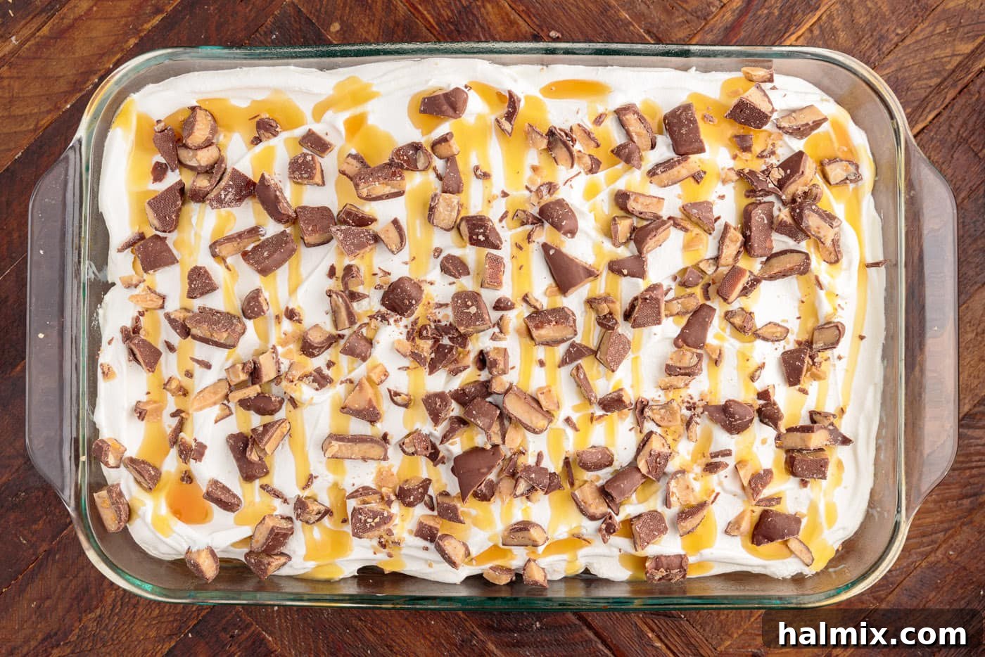 The final touch: caramel drizzled over the Cool Whip and generously sprinkled with chopped Heath bars, creating a stunning and delicious surface.