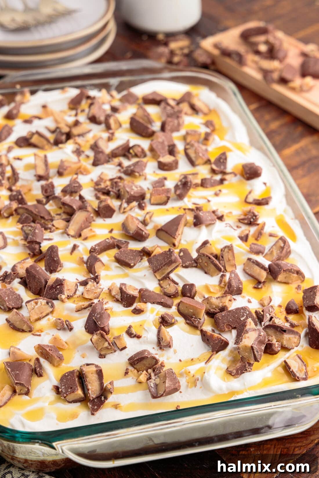 A full pan of Better Than Sex Cake, richly topped with whipped cream and a generous scattering of chopped Heath bars, ready to be served.