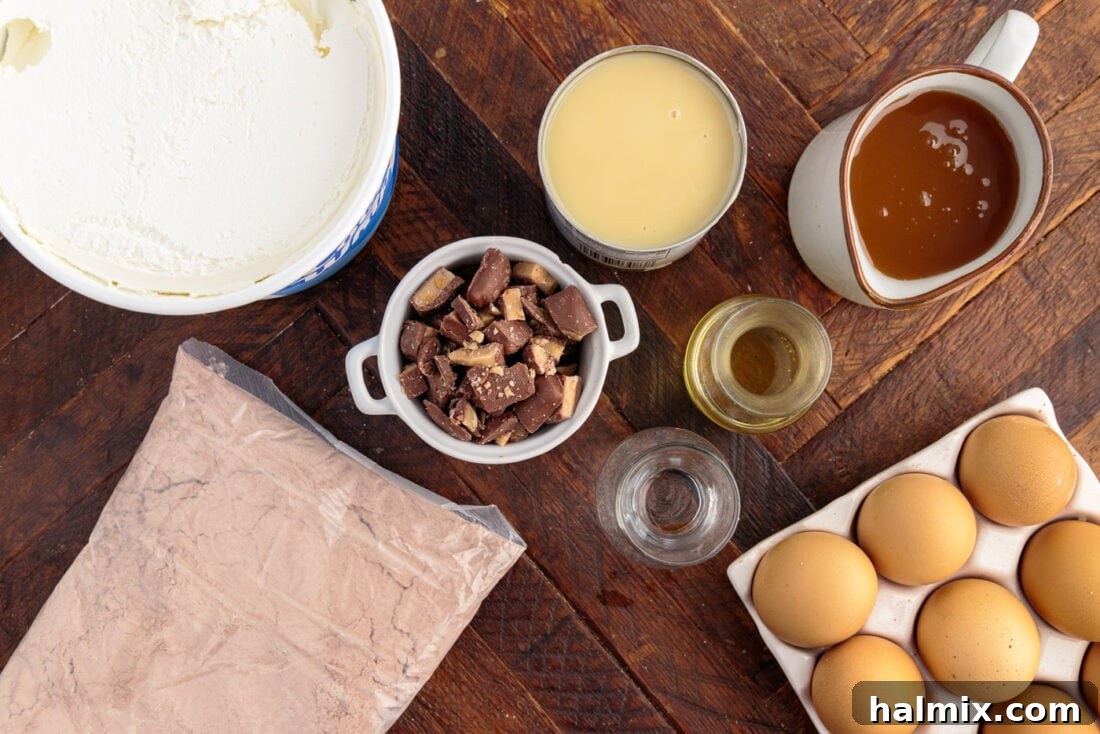A collection of ingredients for Better Than Sex Cake, including a box of cake mix, eggs, oil, water, sweetened condensed milk, caramel sauce, Cool Whip, and Heath bars, neatly arranged on a counter.