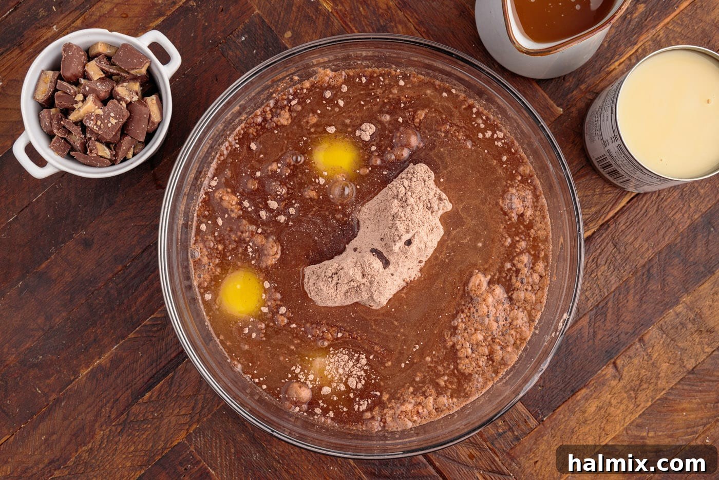 A bowl filled with cake mix, eggs, oil, and water, ready to be mixed, demonstrating the initial steps of preparing the cake.