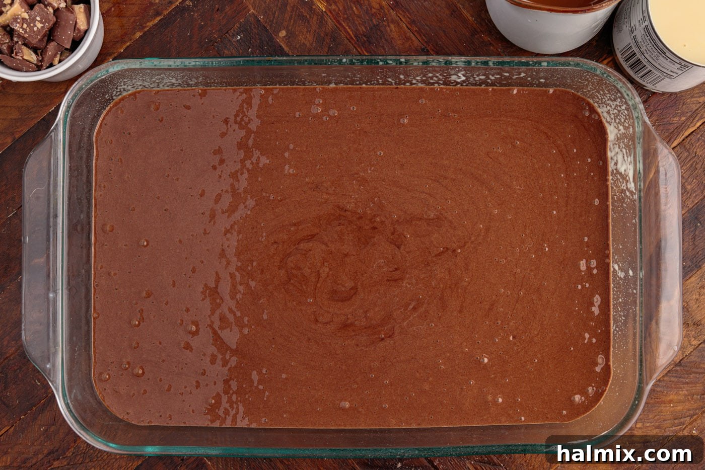 Smooth chocolate devil's food cake batter poured into a 13x9 inch baking dish, prepared for baking.