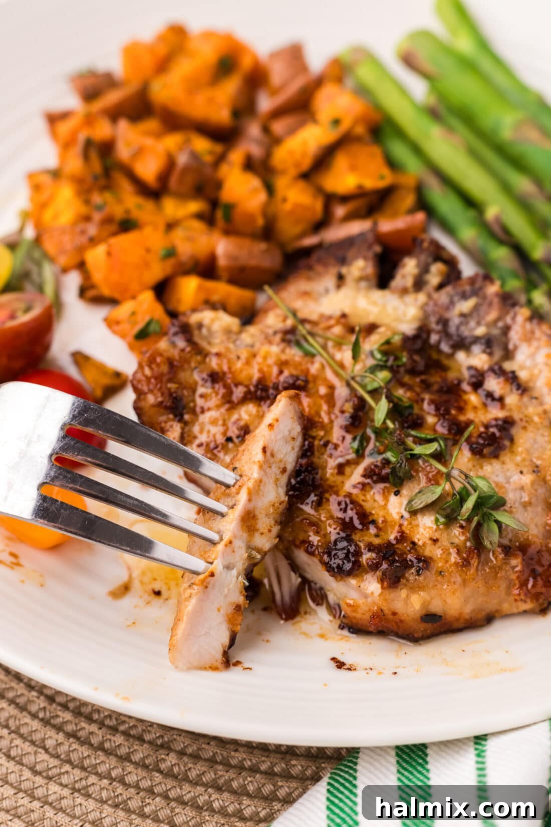 Piece of Garlic Butter Pork Chop on a fork next to a Garlic Butter Pork Chop