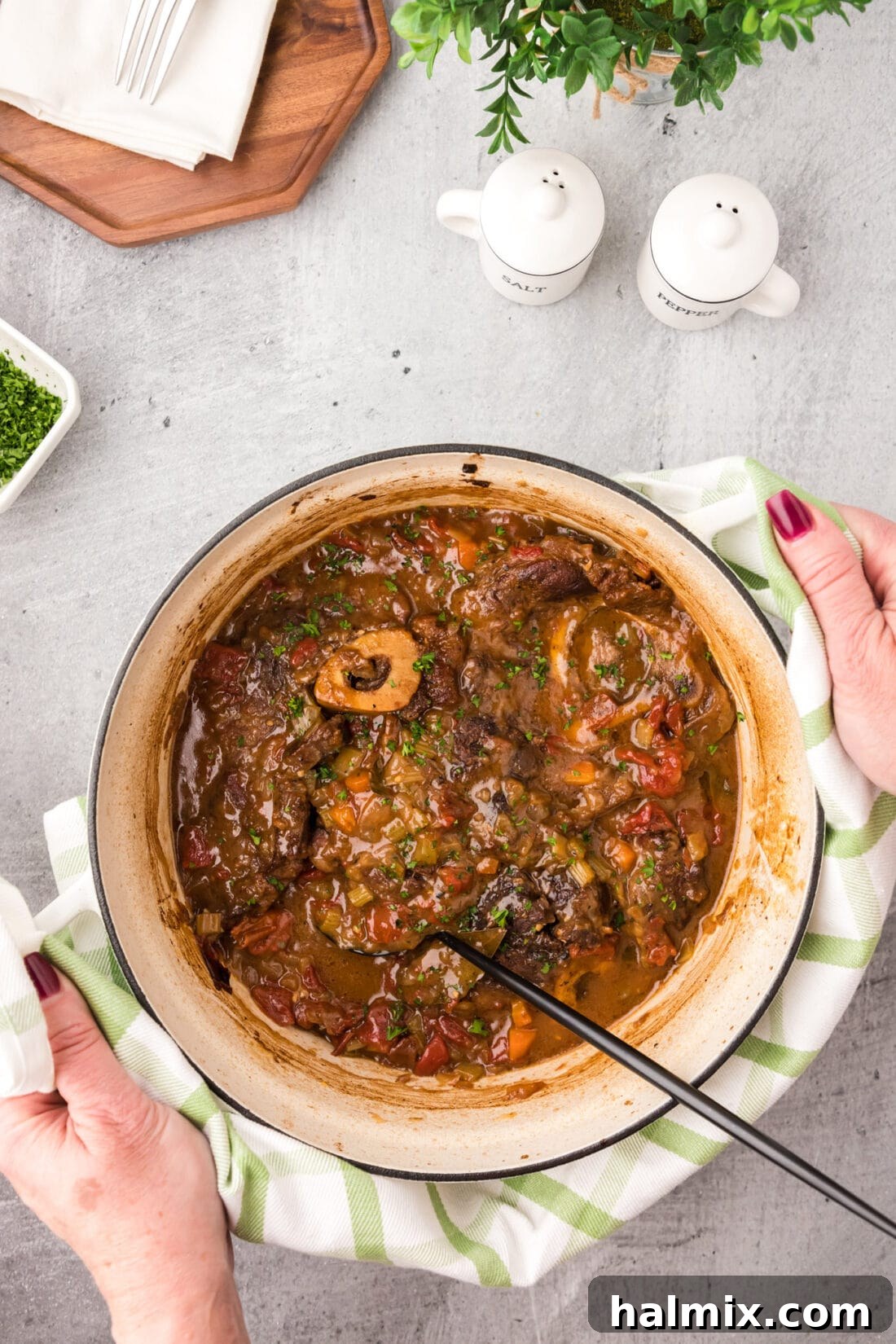 Hands holding a pot of Braised Beef Shanks, ready to be served