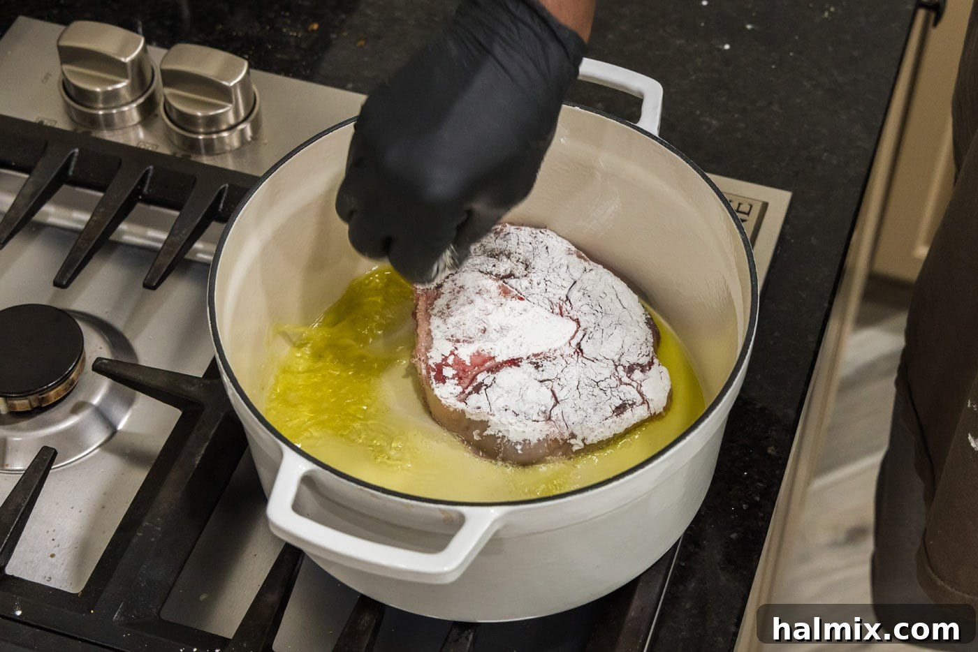 Adding cornstarch coated beef shanks to hot oil in a Dutch oven