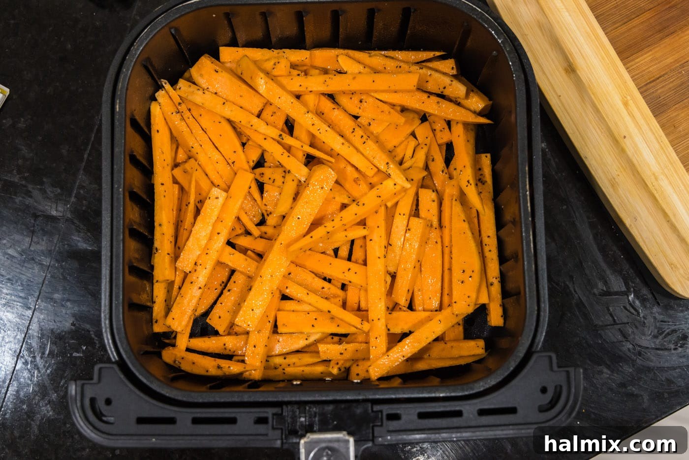 Sweet potato fries arranged in a single layer within an air fryer basket.