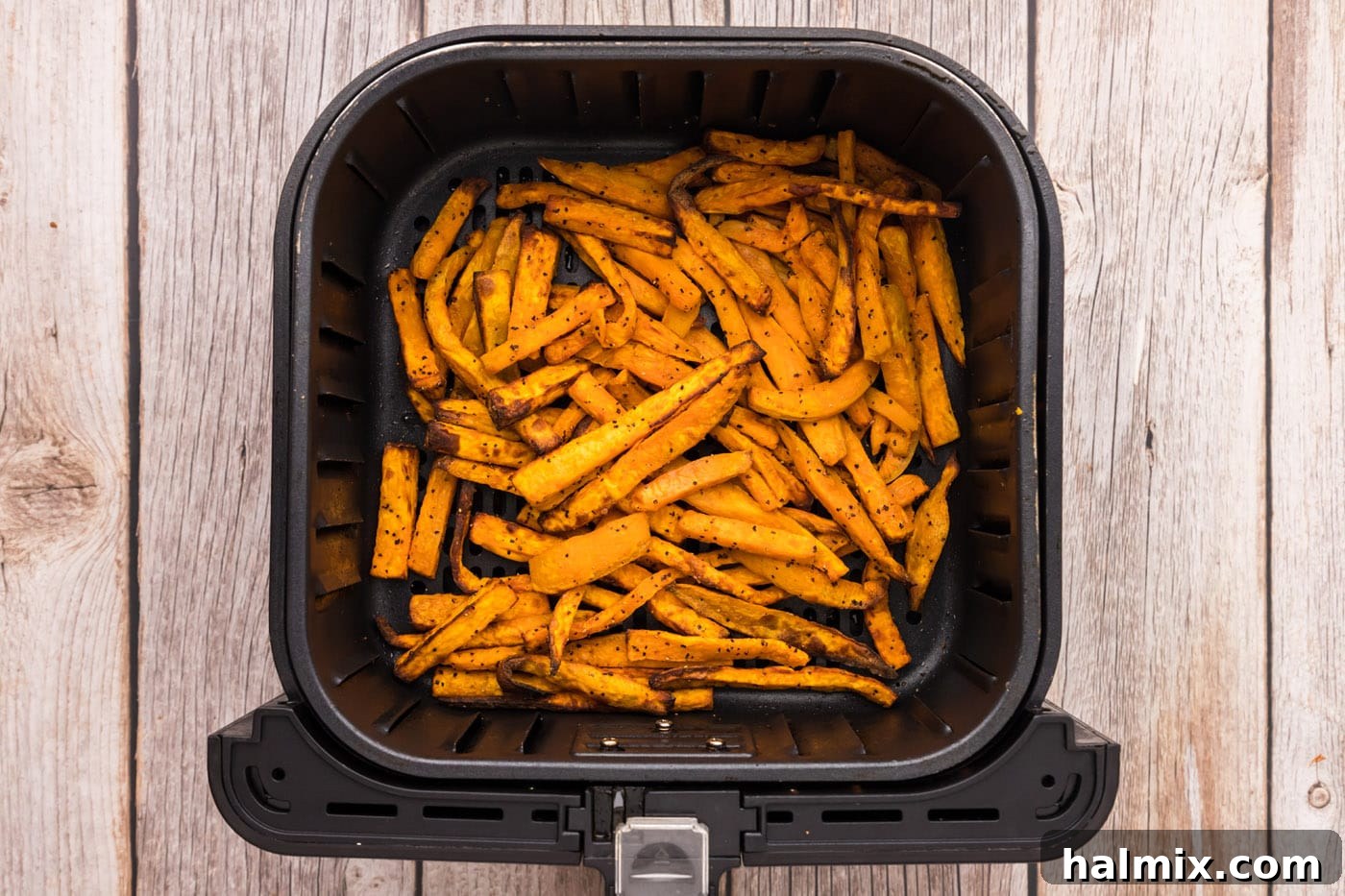 Finished air fryer sweet potato fries in the basket, ready to be served.