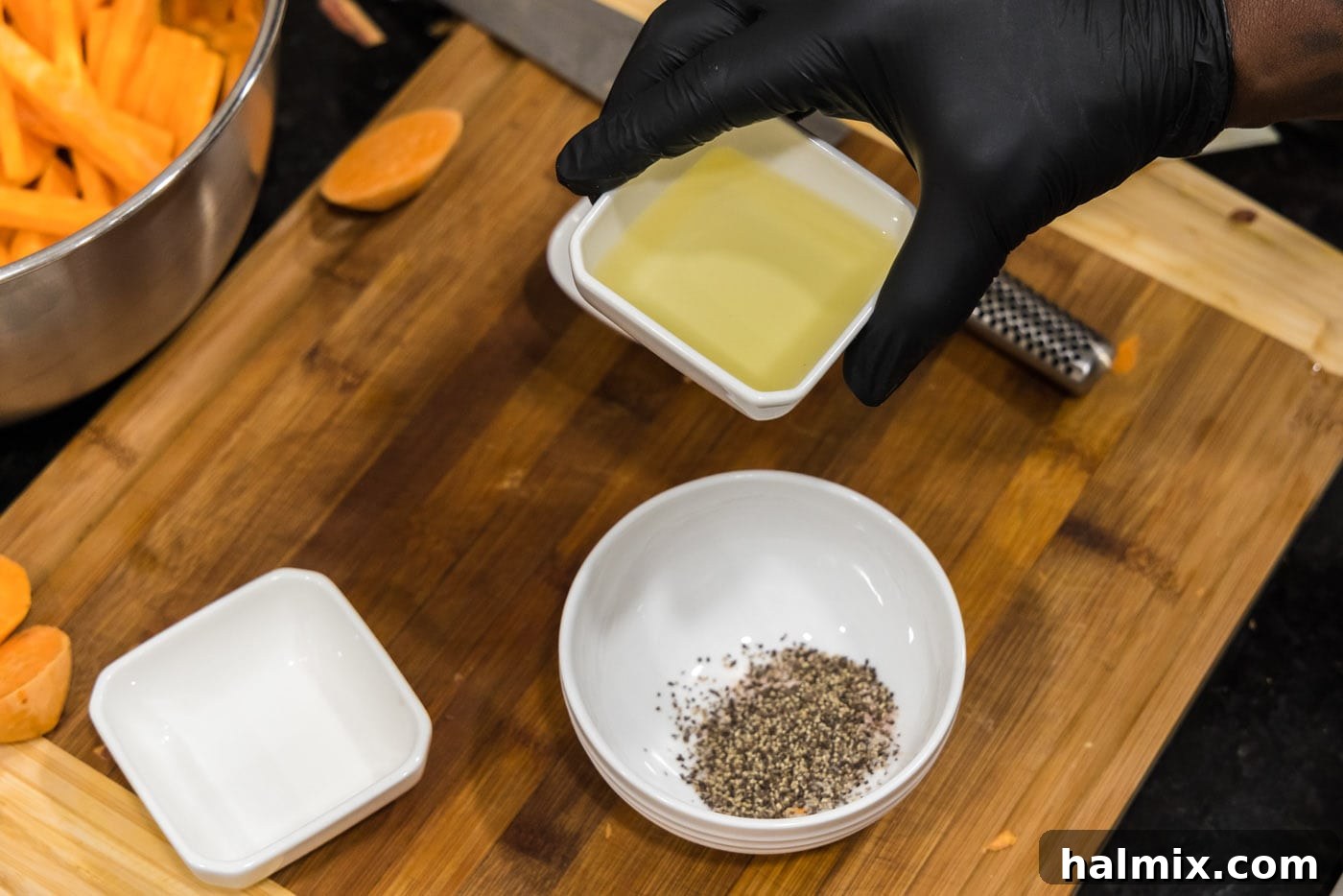 Adding olive oil to a bowl with salt and pepper, preparing the seasoning mixture.