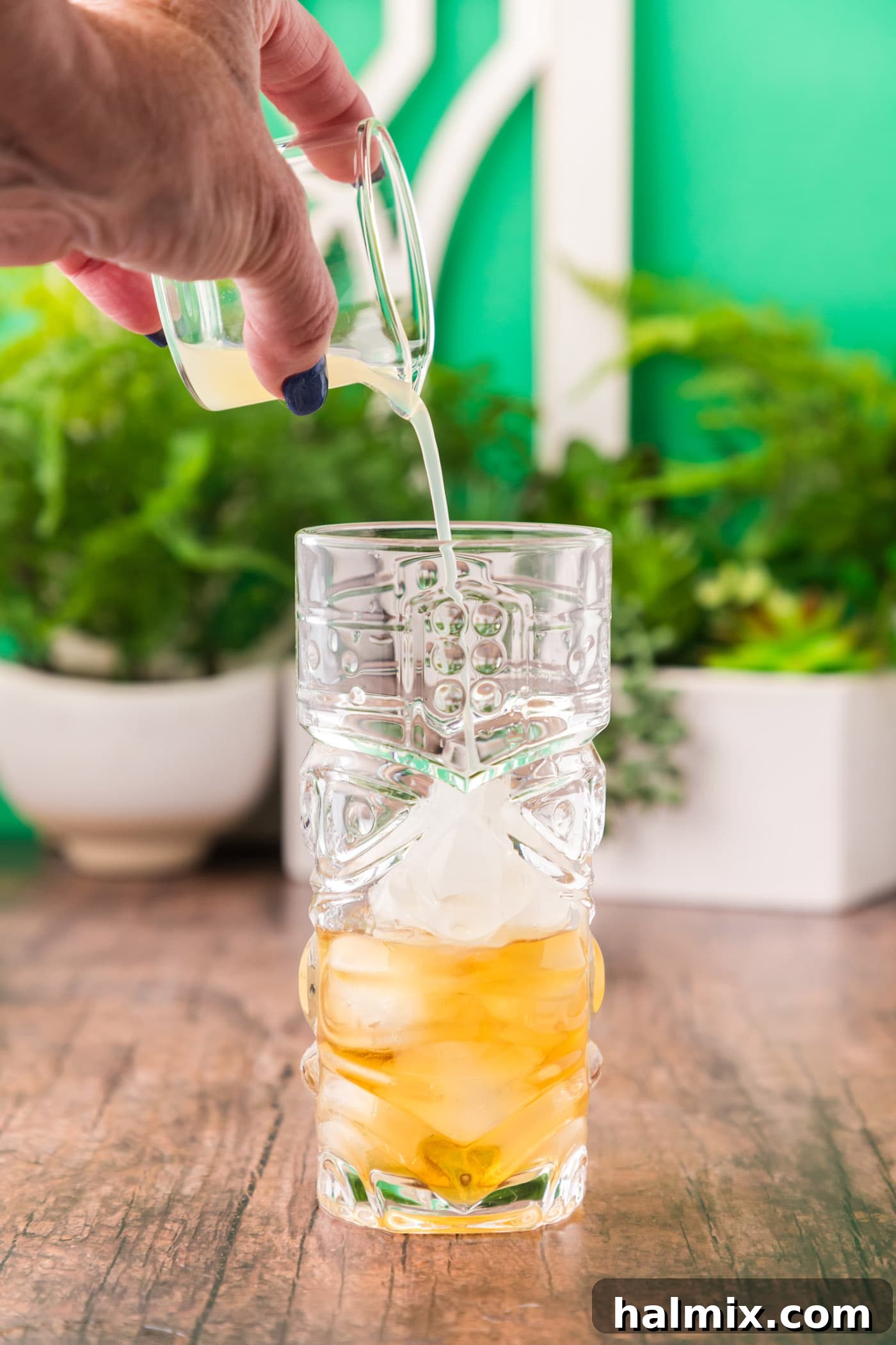 Adding fresh lime juice to the rum and ice in a glass, introducing a vibrant citrus note.