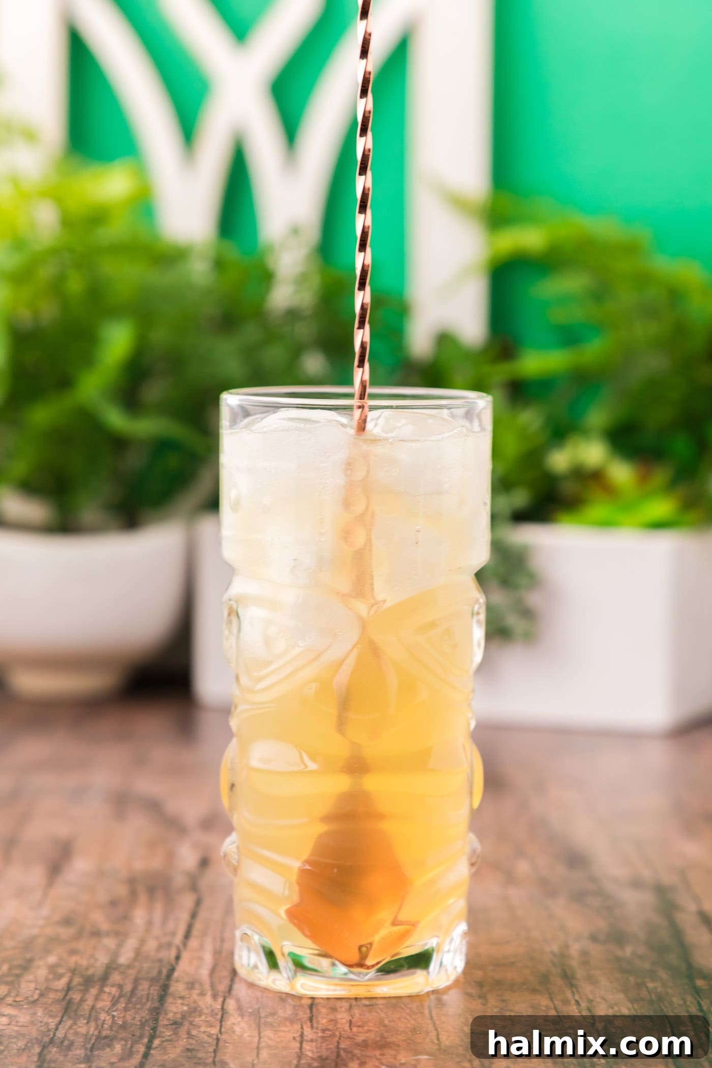 A cocktail spoon gently stirring the Jamaican rum cocktail, ensuring the ingredients are well combined.