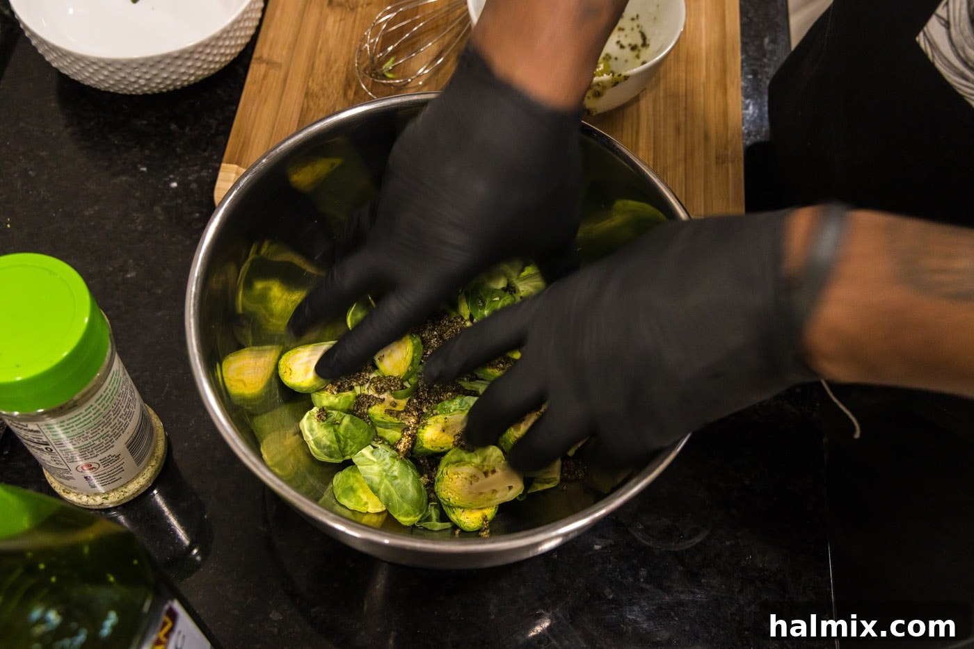 hands mixing brussels sprouts with oil and seasonings