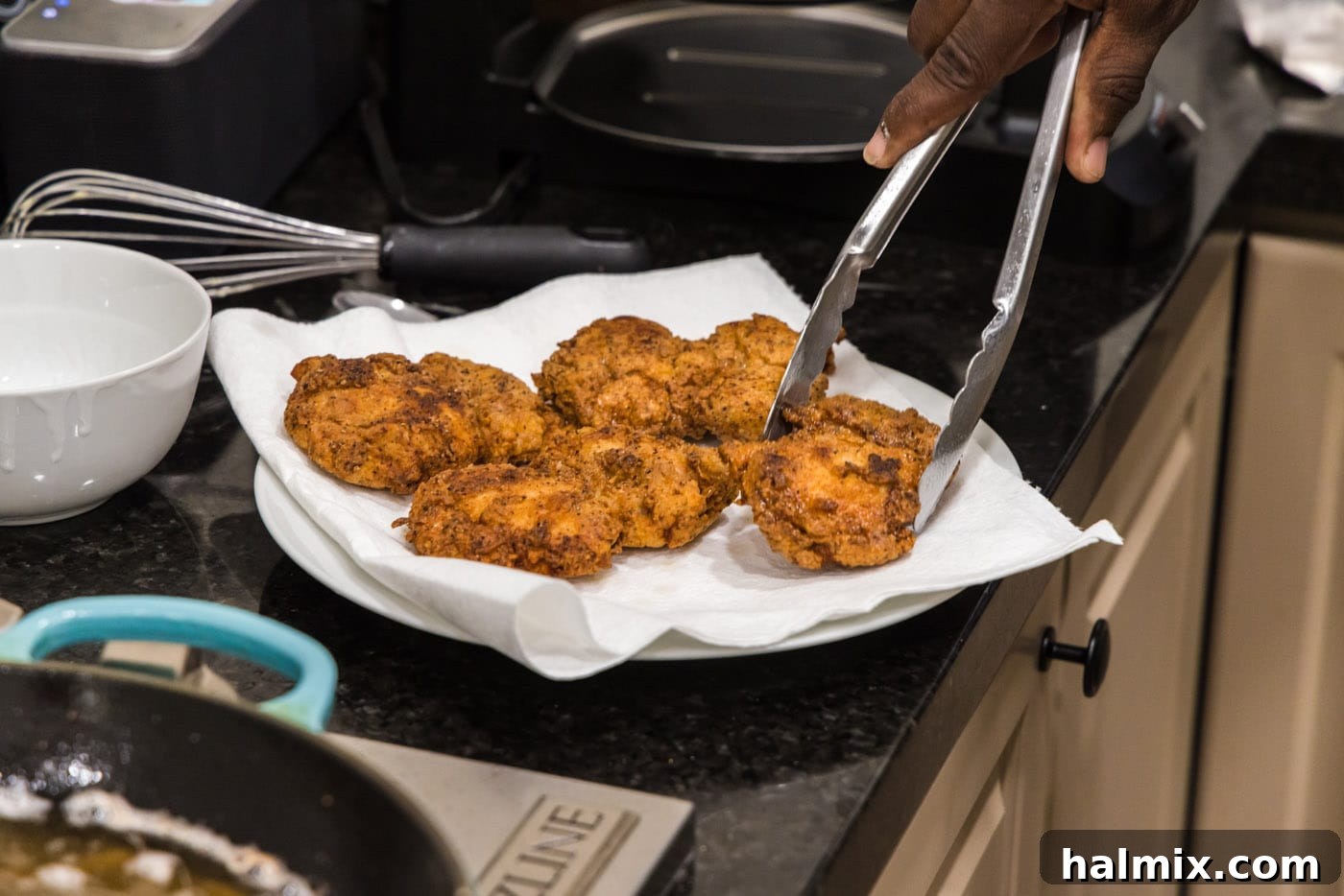 Southern Fried Bliss 16 Crispy fried boneless chicken thighs resting on a paper towel-lined plate after frying