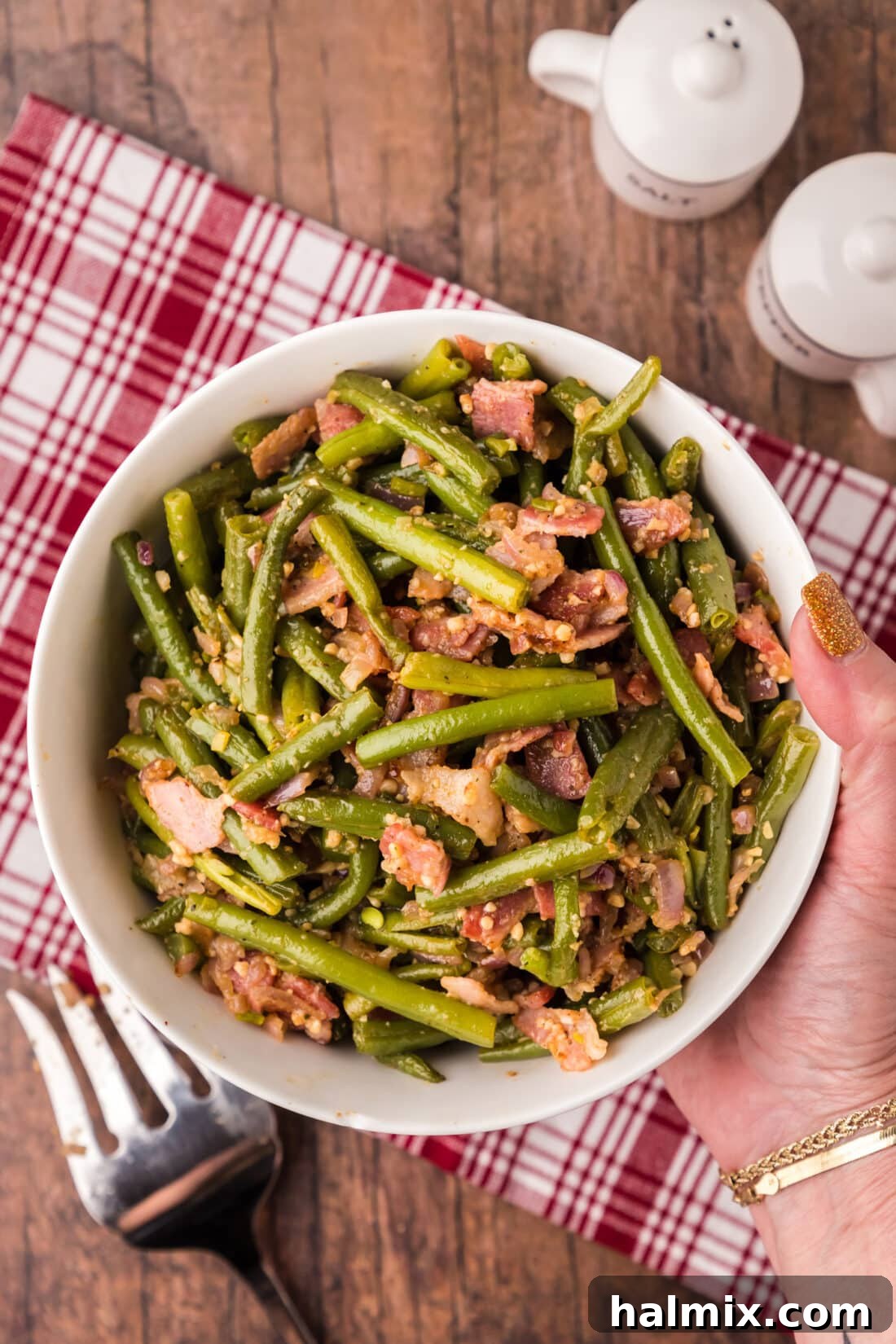 Old Fashioned Southern Green Beans 2 Hand holding a bowl of Southern Green Beans with visible bacon and shallots