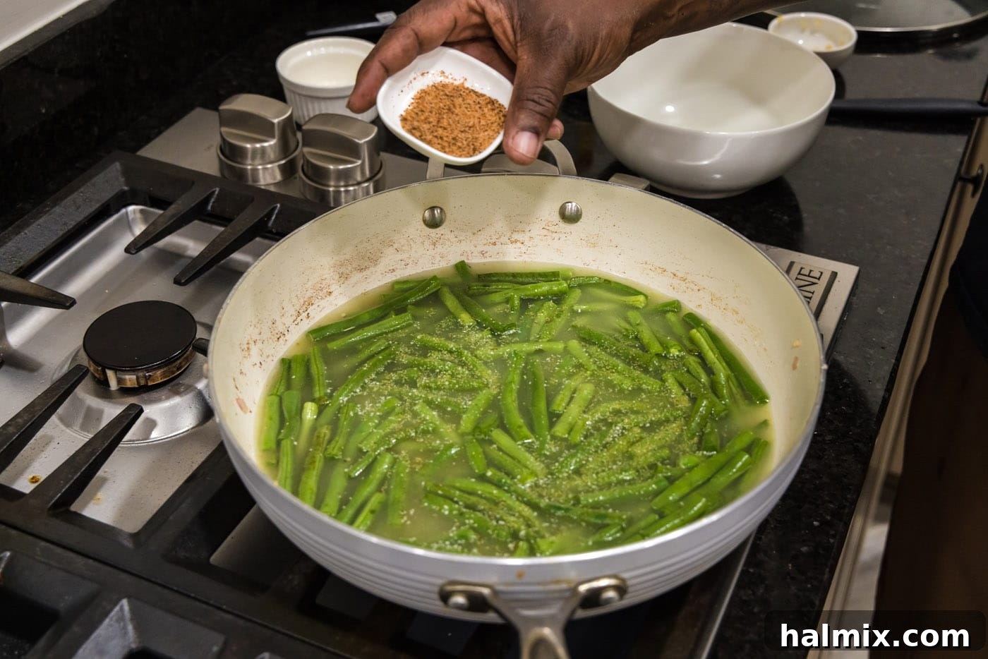 Old Fashioned Southern Green Beans 9 Adding Cajun seasoning to green beans simmering in a skillet
